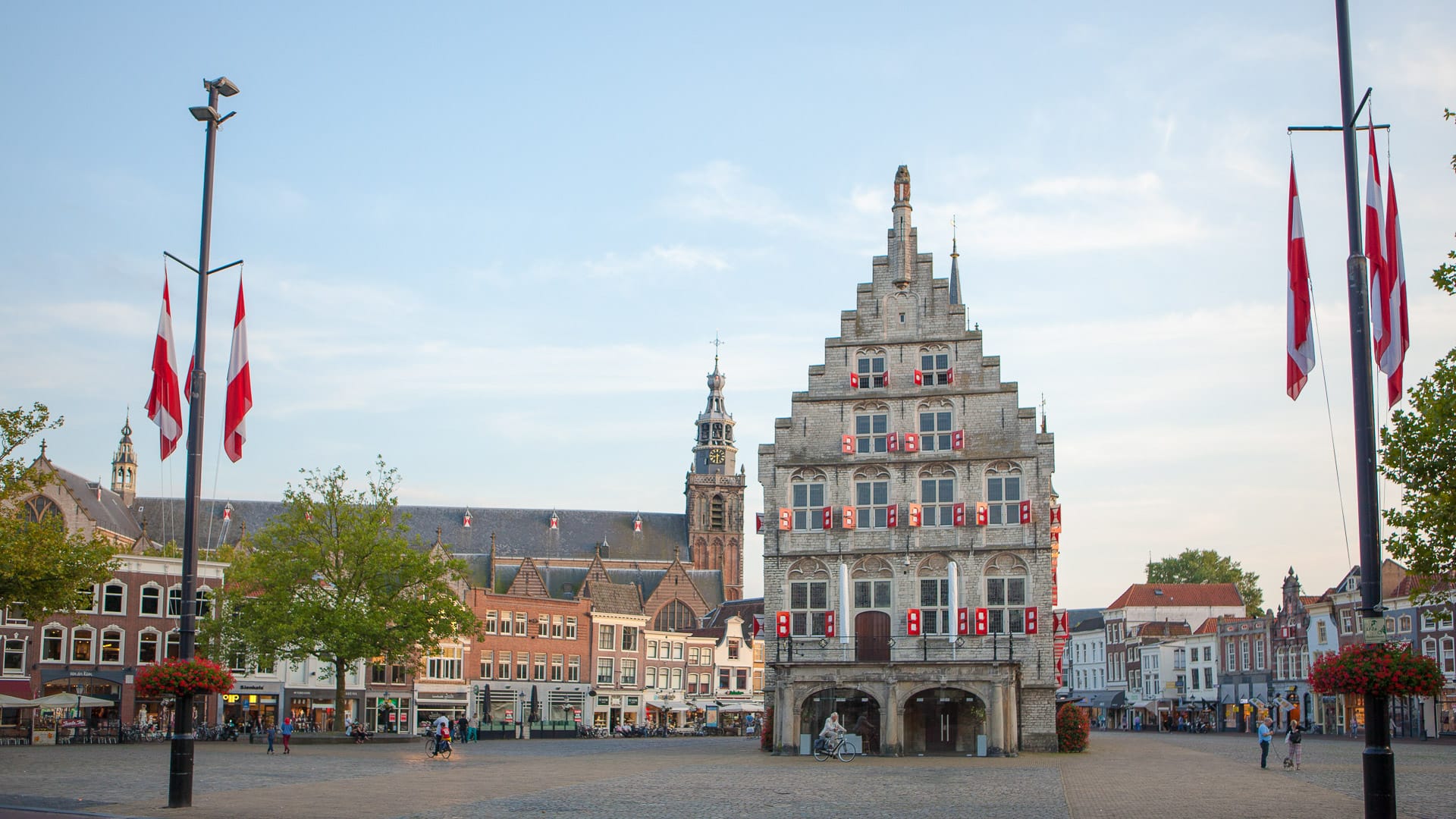 Historic market square on the Amsterdam to Bruges cycling route with Dutch town hall and flags