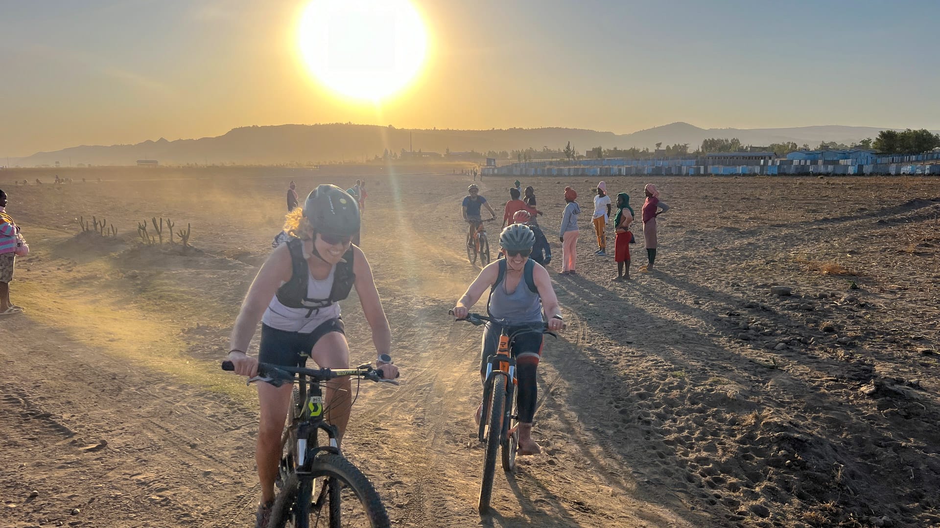 Cyclists riding across dusty farmland at sunset during a guided cycling trip in Ethiopia