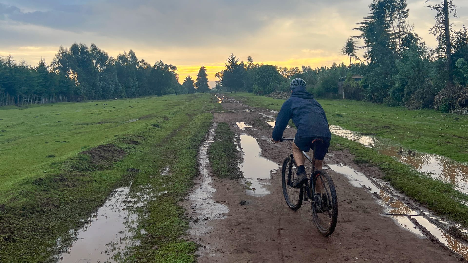 Cyclist riding along a muddy dirt track during an off-road ride in rural Ethiopia