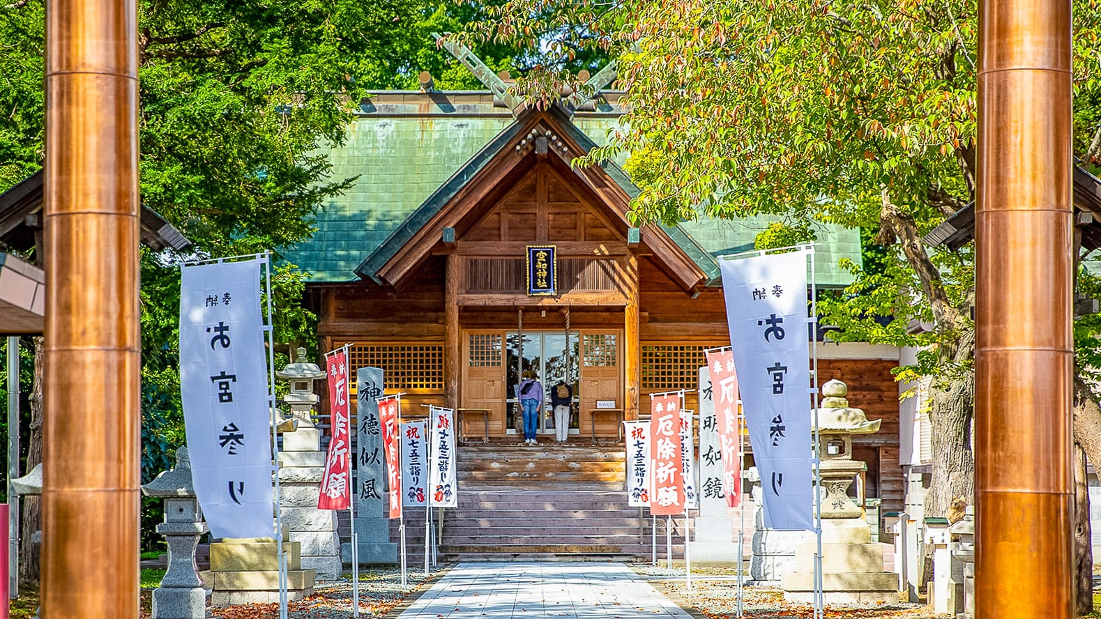Traditional wooden shrine surrounded by trees and banners in Hokkaido Japan