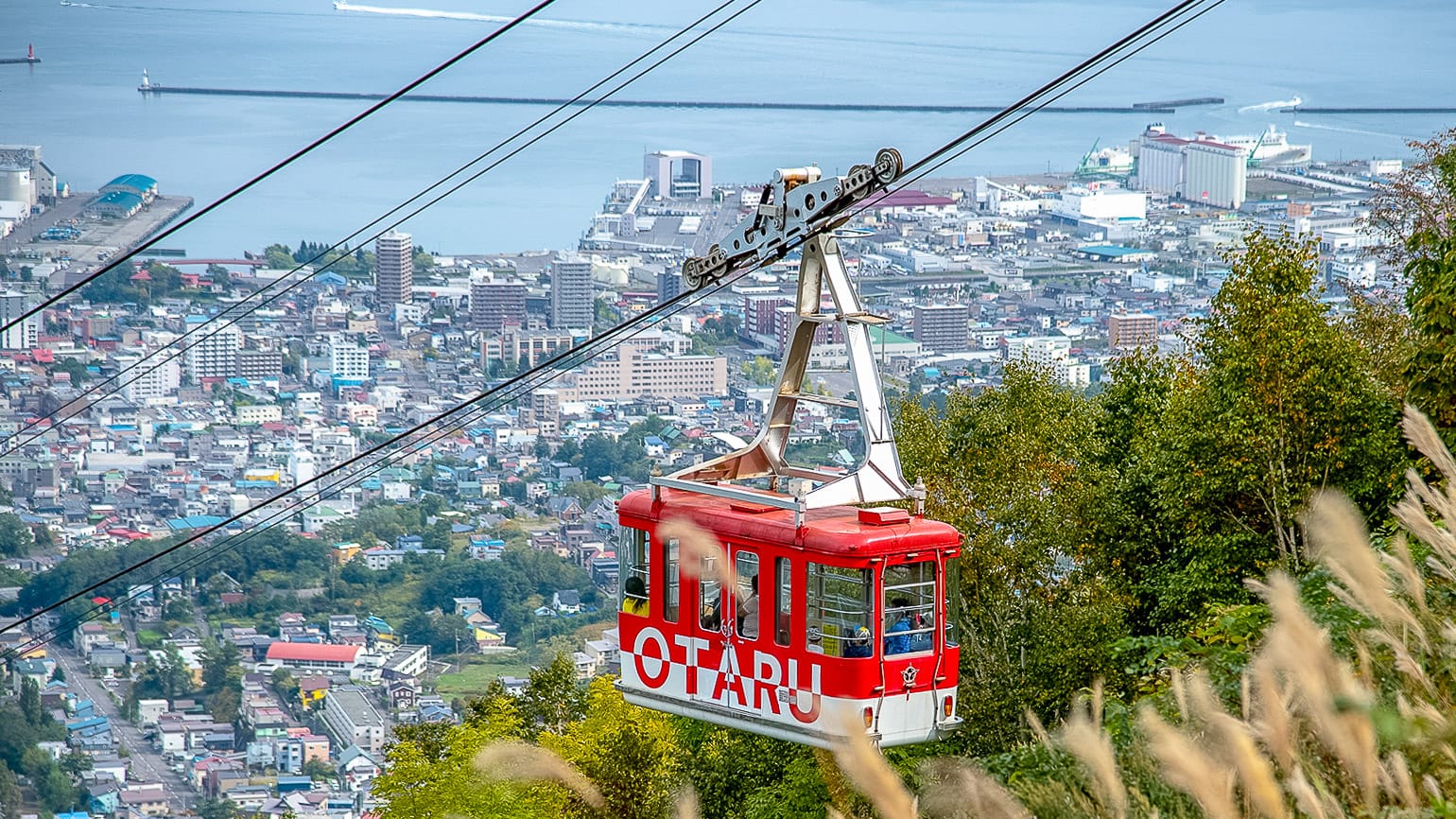 Red Otaru cable car climbing above the city with sea views in Hokkaido Japan