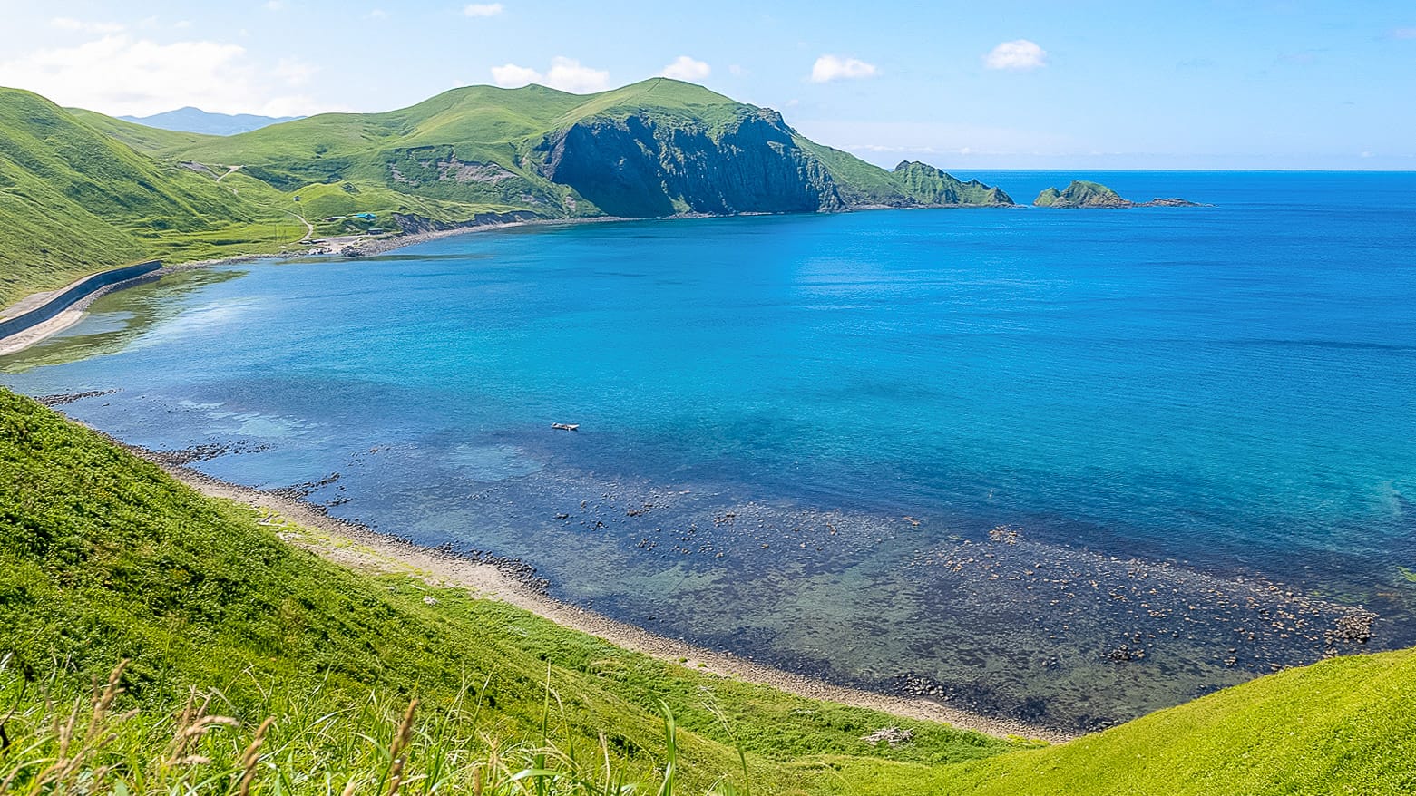 Bright summer coastline with clear blue sea and green hills in Hokkaido Japan
