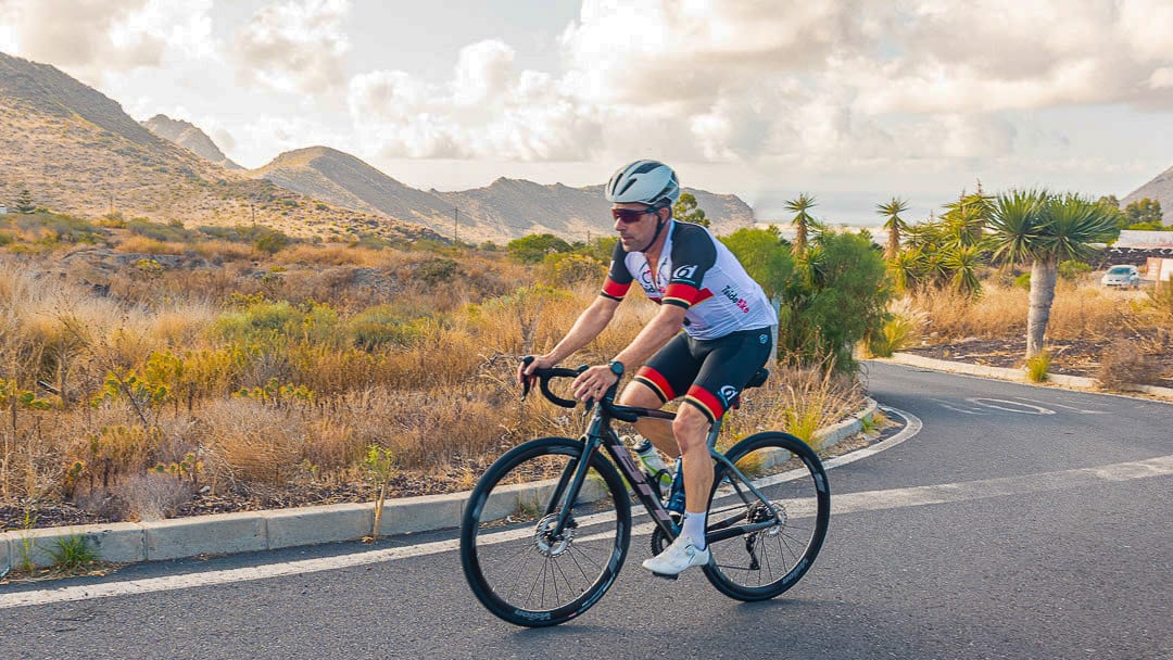 Cyclist riding a quiet road in Tenerife with dry landscape and mountain views