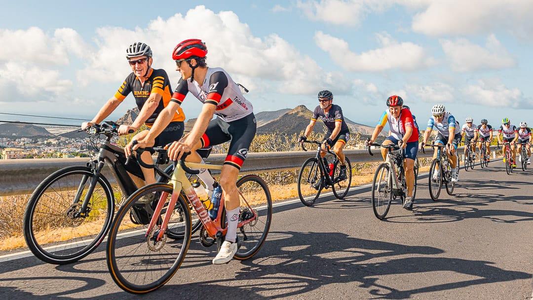 Large group of cyclists riding together on a scenic road in Tenerife