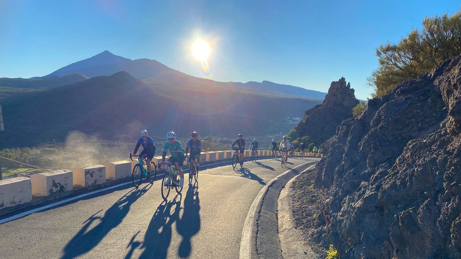 Cyclists riding a mountain road in Tenerife with Mount Teide visible at sunrise