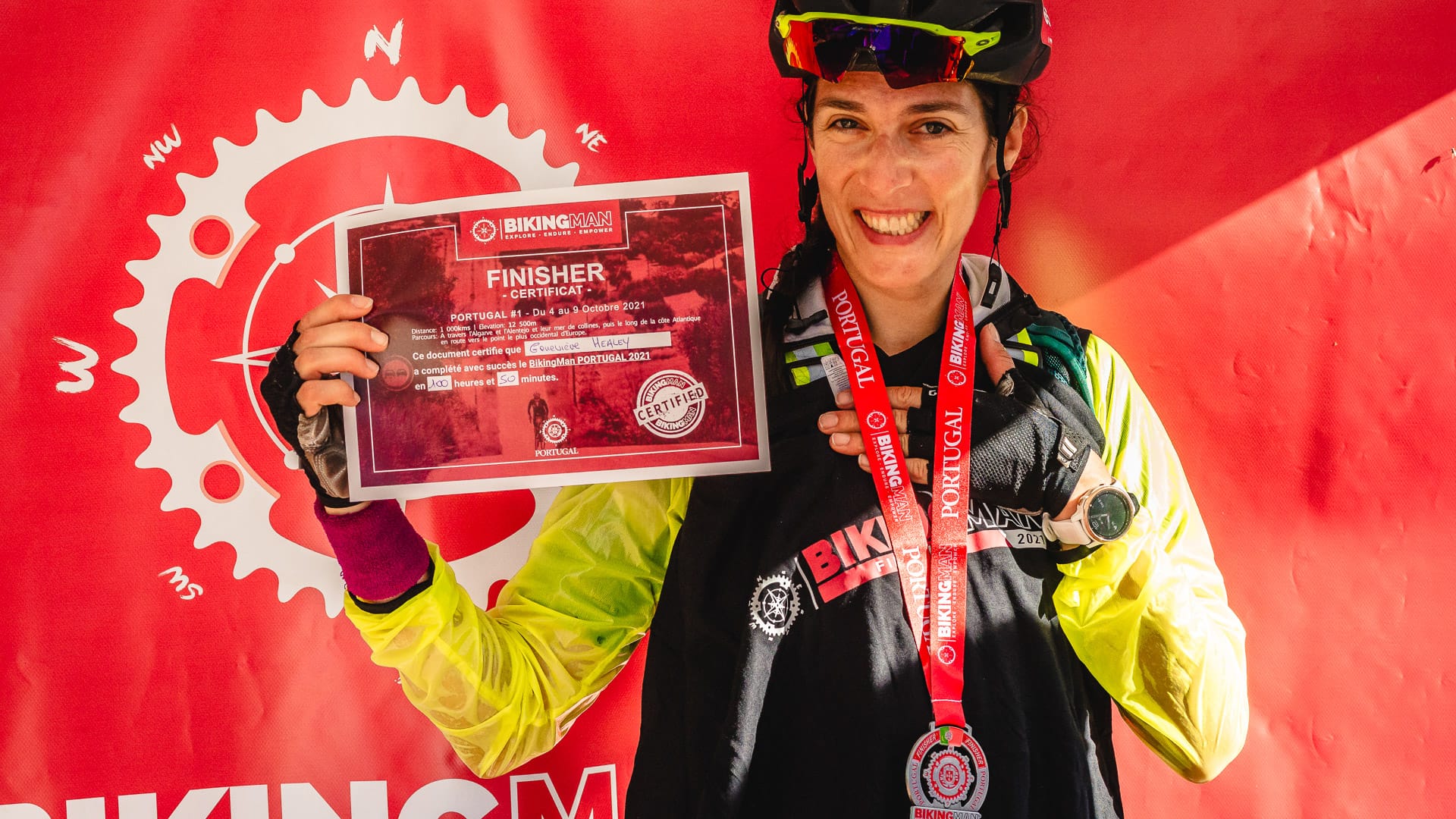 Smiling cyclist holding finisher certificate at the BikingMan Portugal finish line