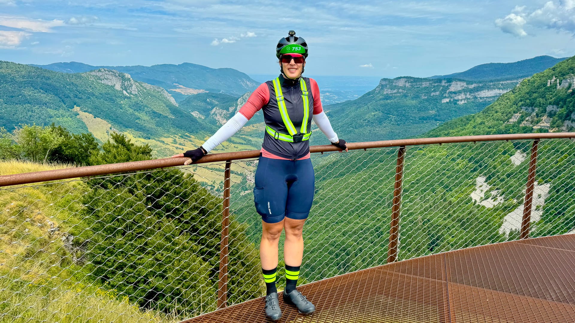 Cyclist standing at a viewpoint overlooking the mountains near Omblèze in Auvergne Rhône-Alpes France