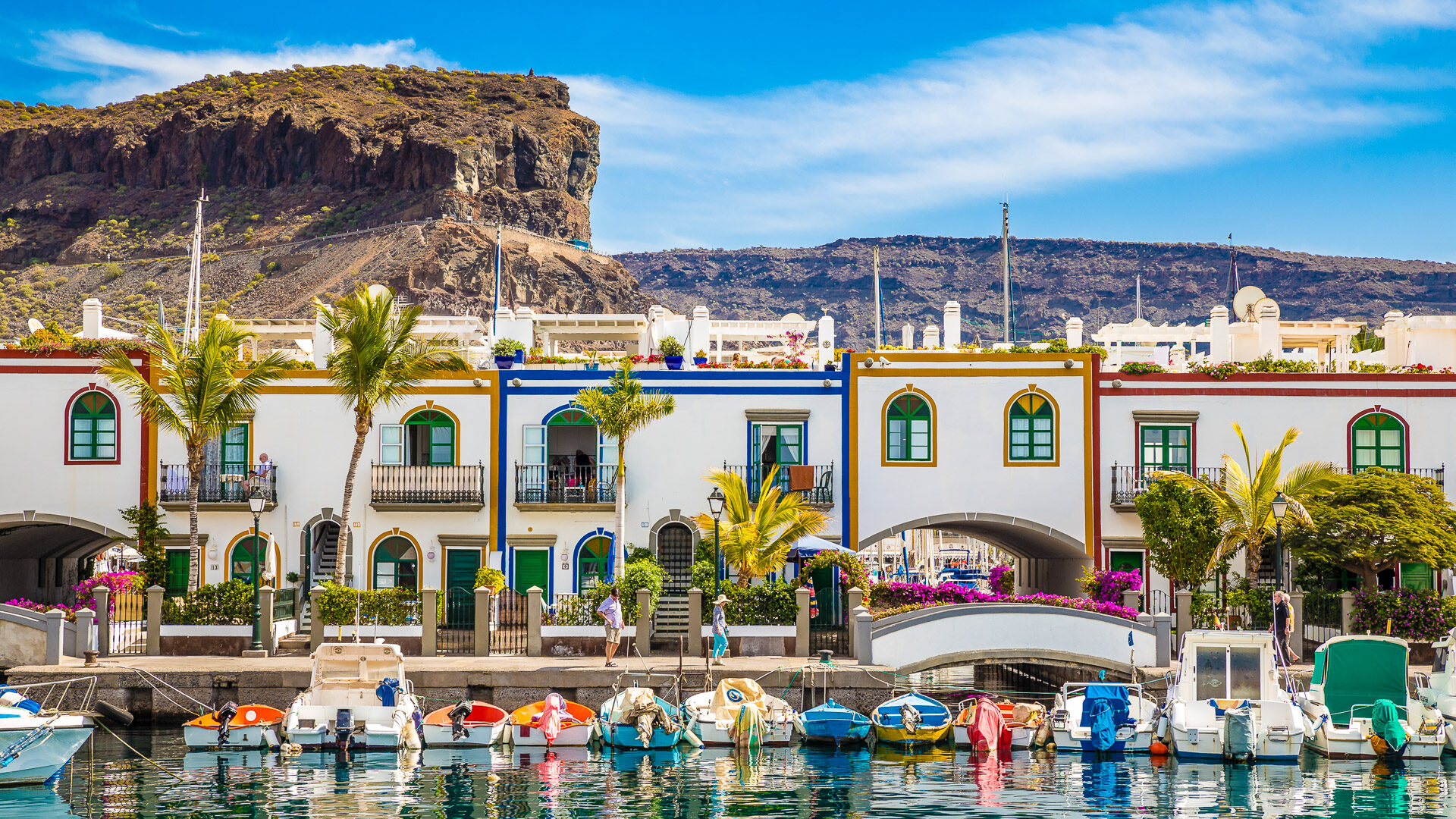 Traditional Colorful Buildings With Boats In Front And Mountain In The Backsground - Puerto de Mogan, Gran Canaria, Canary Islands, Spain