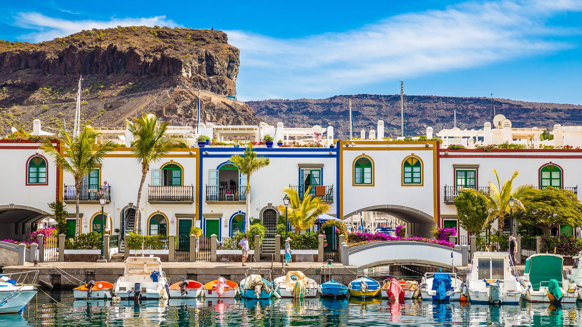 Traditional Colorful Buildings With Boats In Front And Mountain In The Backsground - Puerto de Mogan, Gran Canaria, Canary Islands, Spain