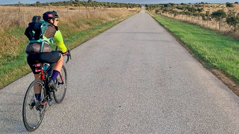 Bikepacker cycling along a long straight country road