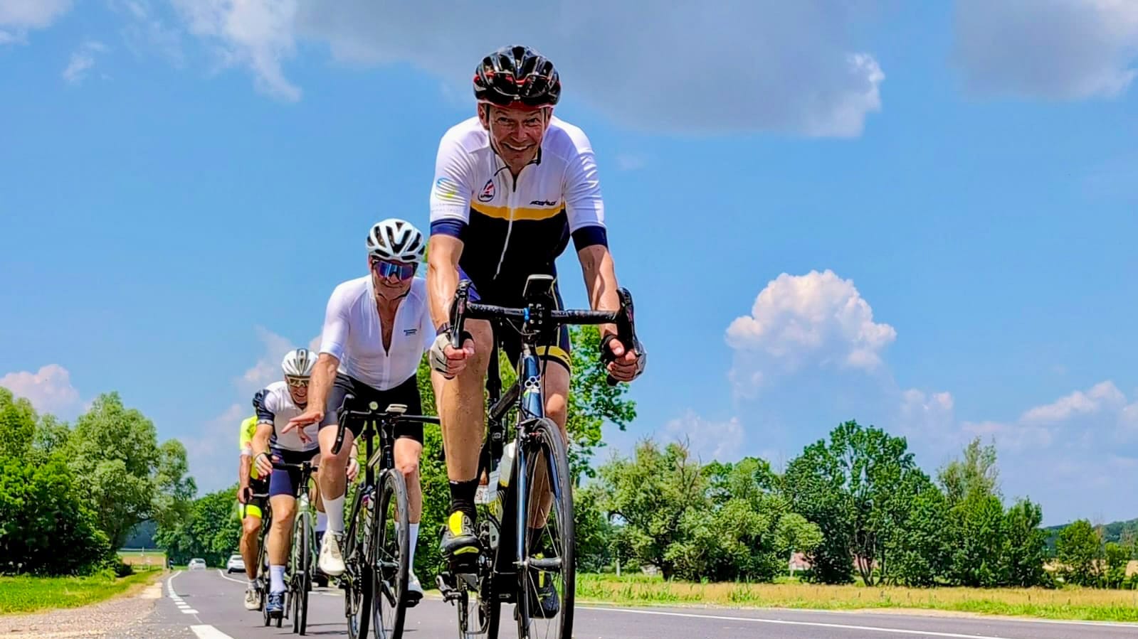 Group of cyclists riding in close formation on quiet French road during Tour de France route trip