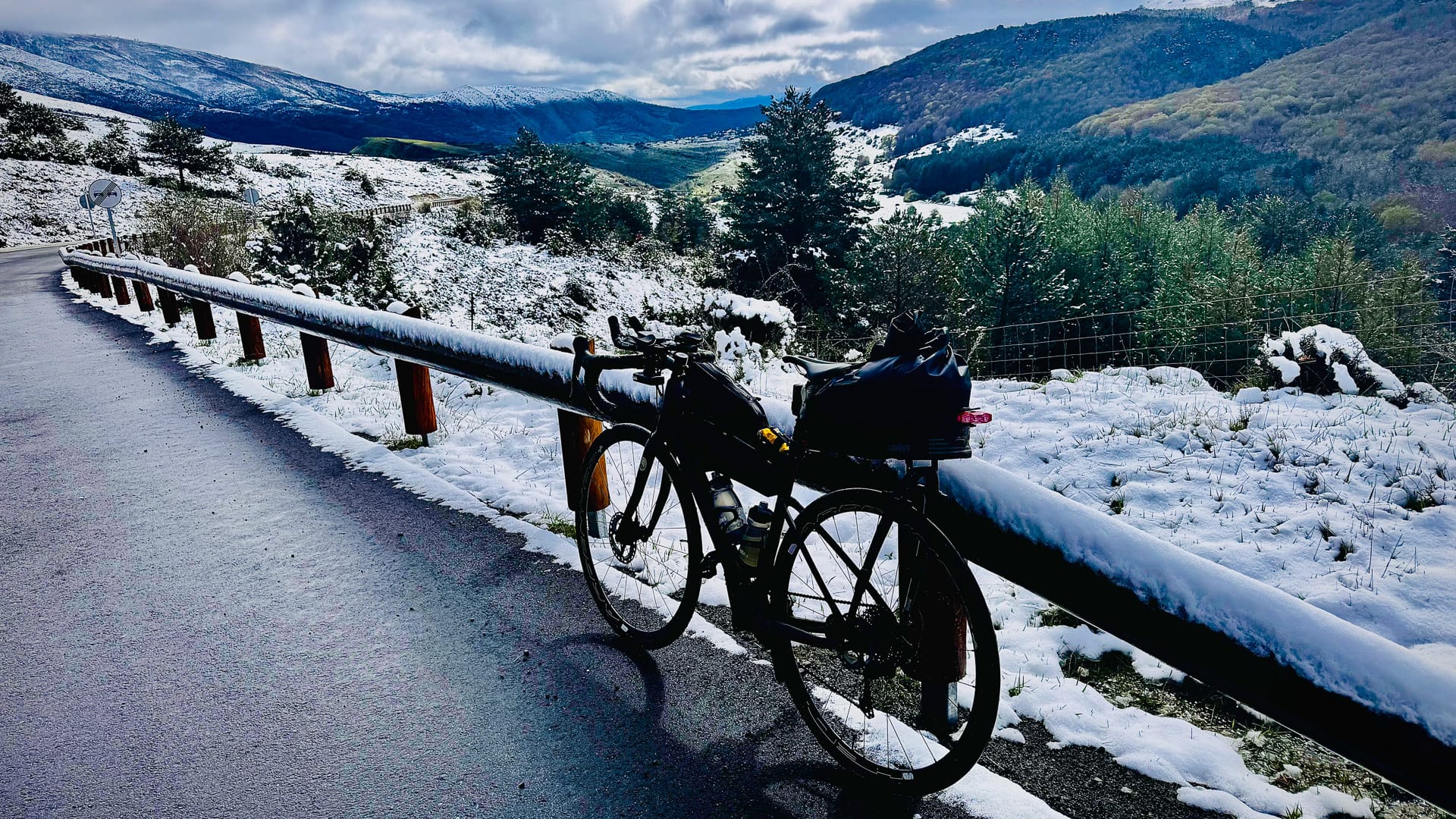 Touring bike parked beside a snow-covered mountain road