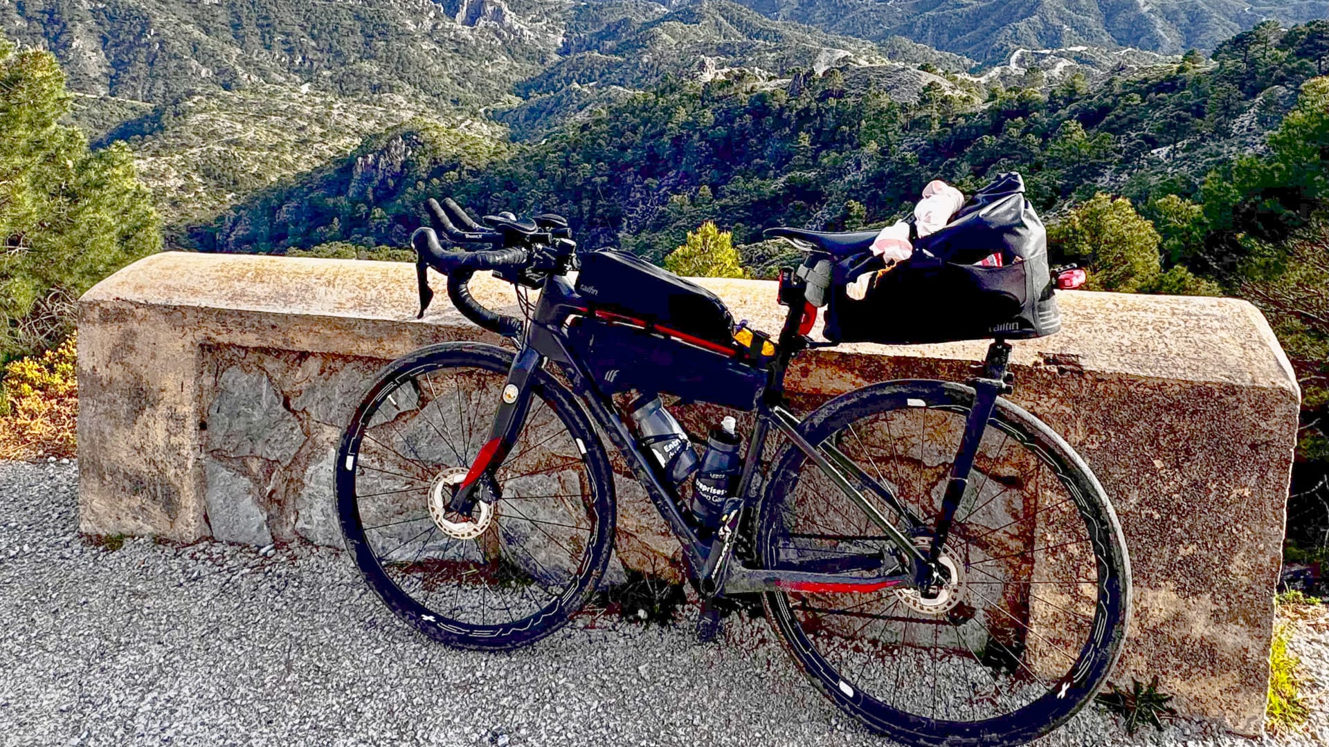 Fully loaded ultra cycling bike resting by a stone wall overlooking the valley in Otivar Spain