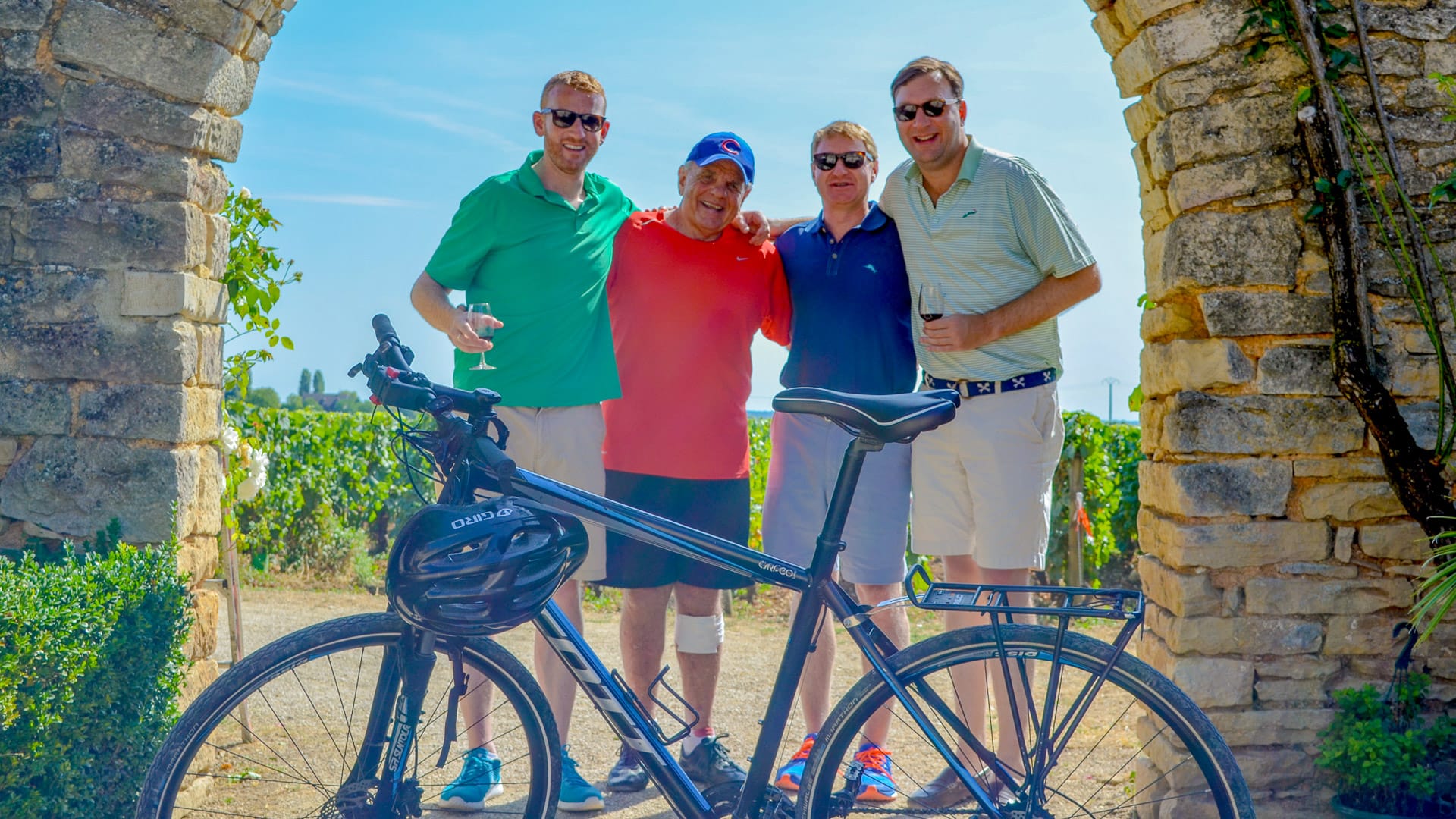 Four men posing for a photo with Burgundy vineyards in the background, France