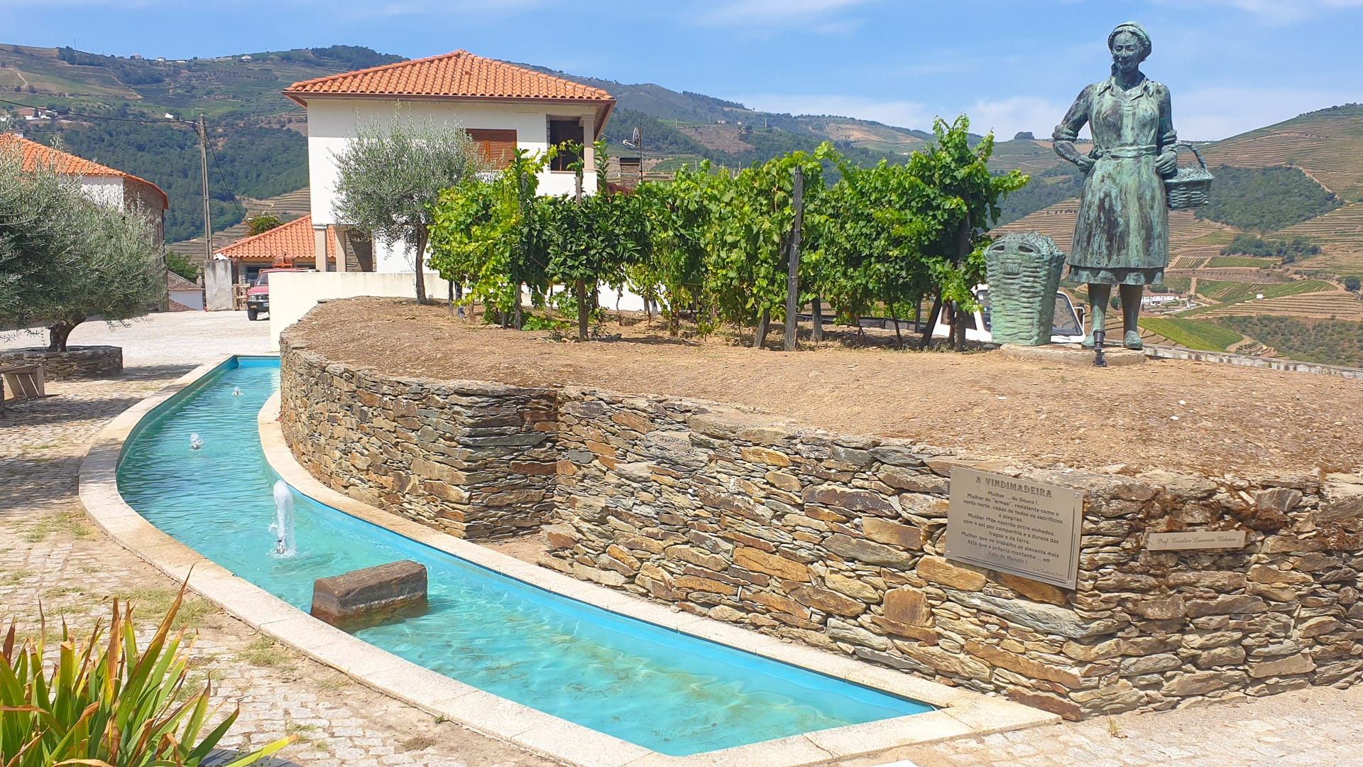 Statue on top of a post reading “A Vindimadeira” and “Mãe… do Douro!” in the Douro Valley, Portugal