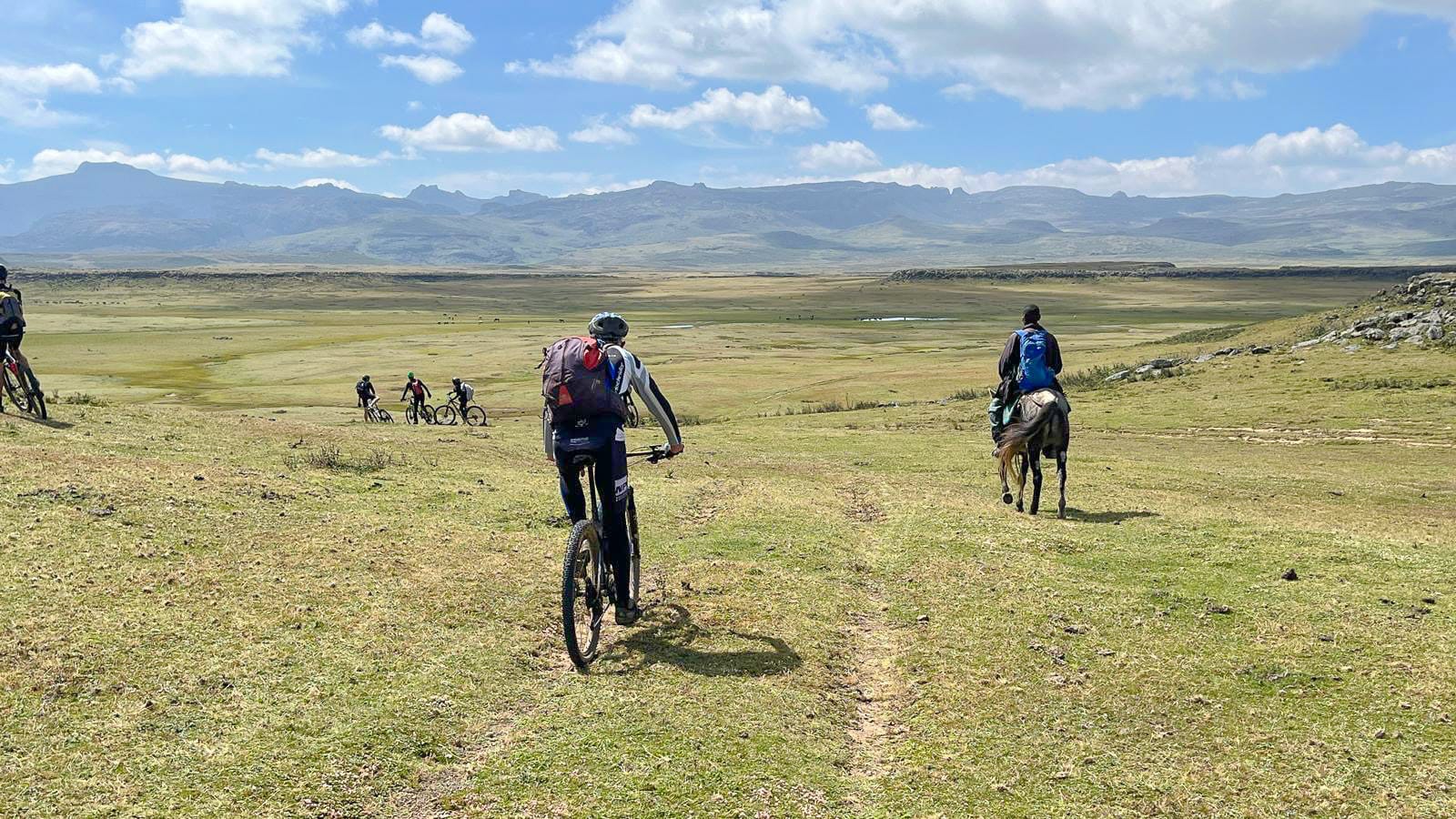 Cyclists riding across flat grasslands in the Bale Mountains, Ethiopia