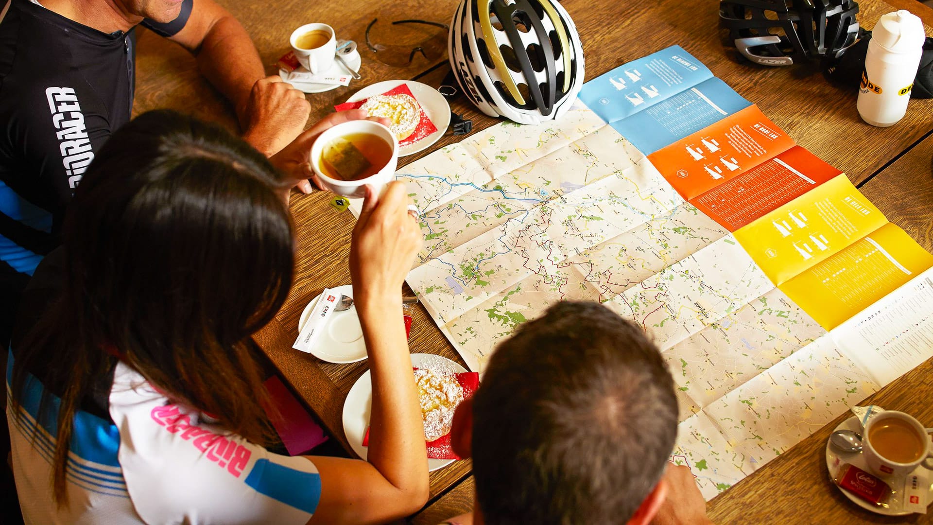 Three cyclists are drinking tea and looking at the map for bike tour in Belgium