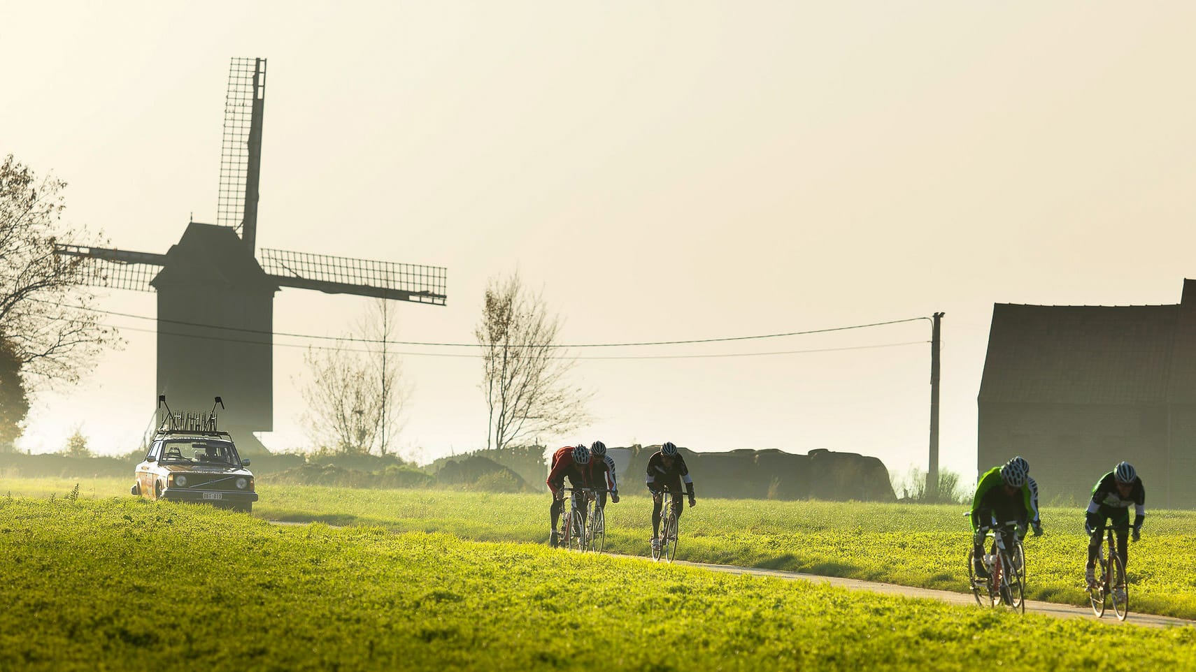 Cyclists on a Belgium cycling holiday with windmill backdrop