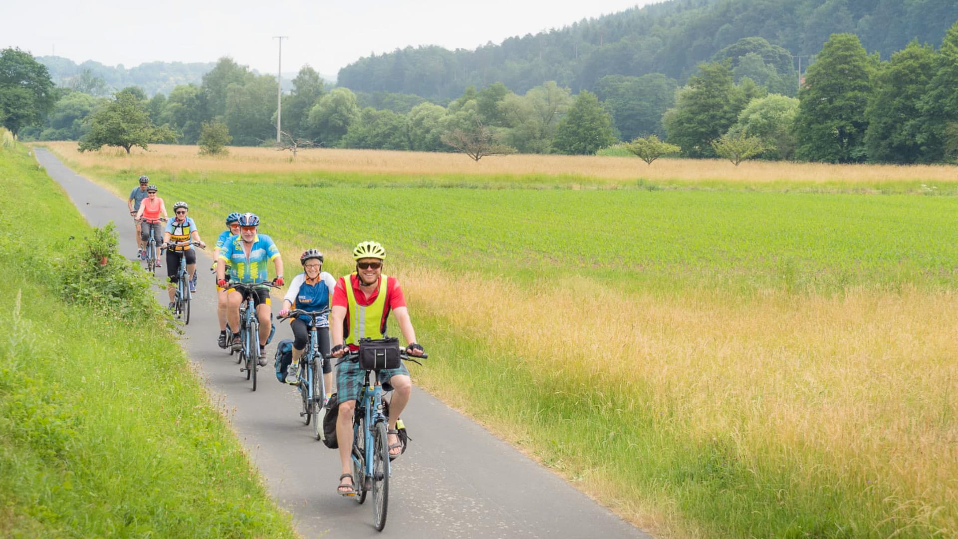 Senior cyclists on a paved path winding through a lush, open landscape