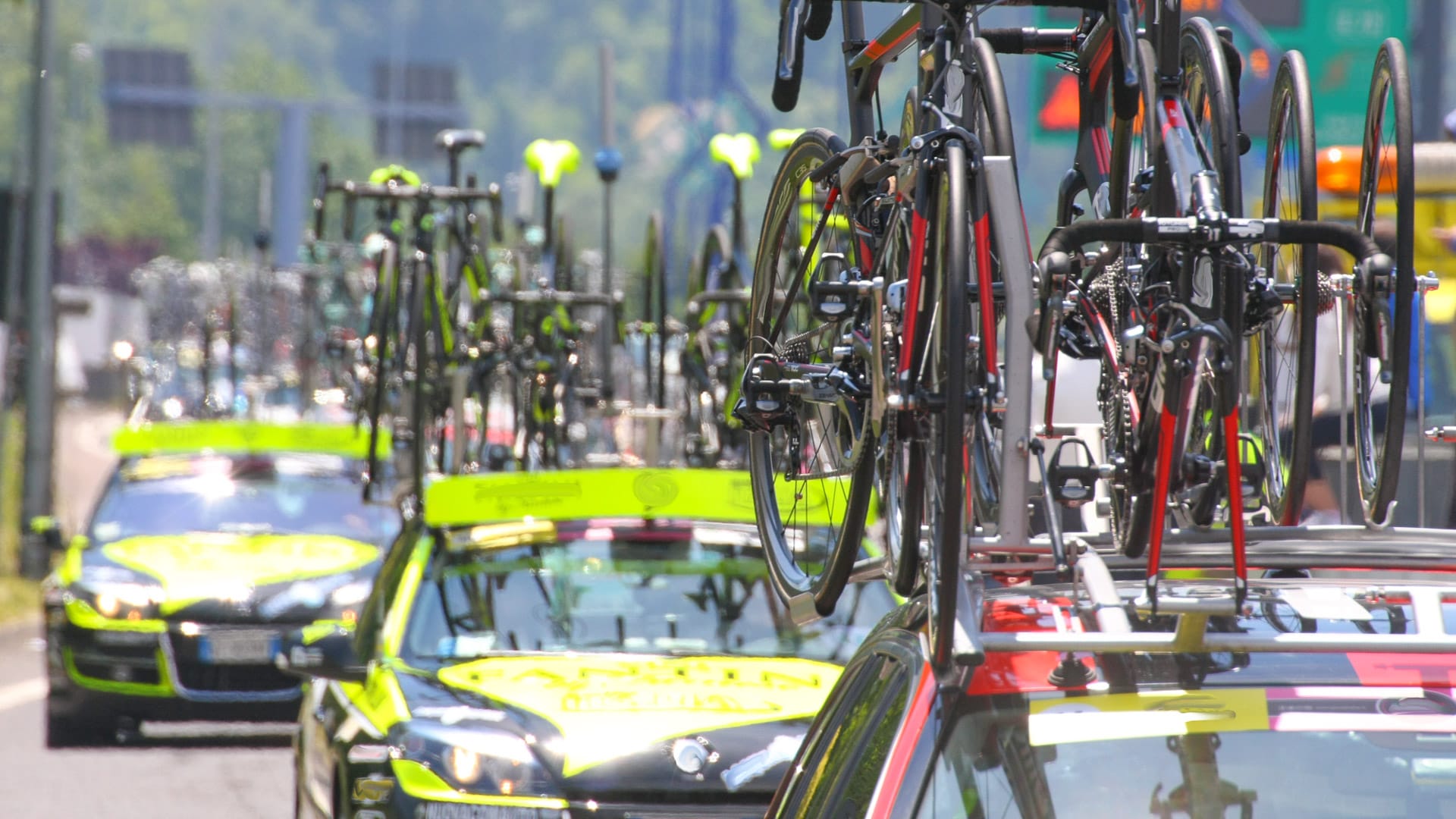 Powerful machines with bicycles flagships Commons follow cyclists during the cycling race in the street
