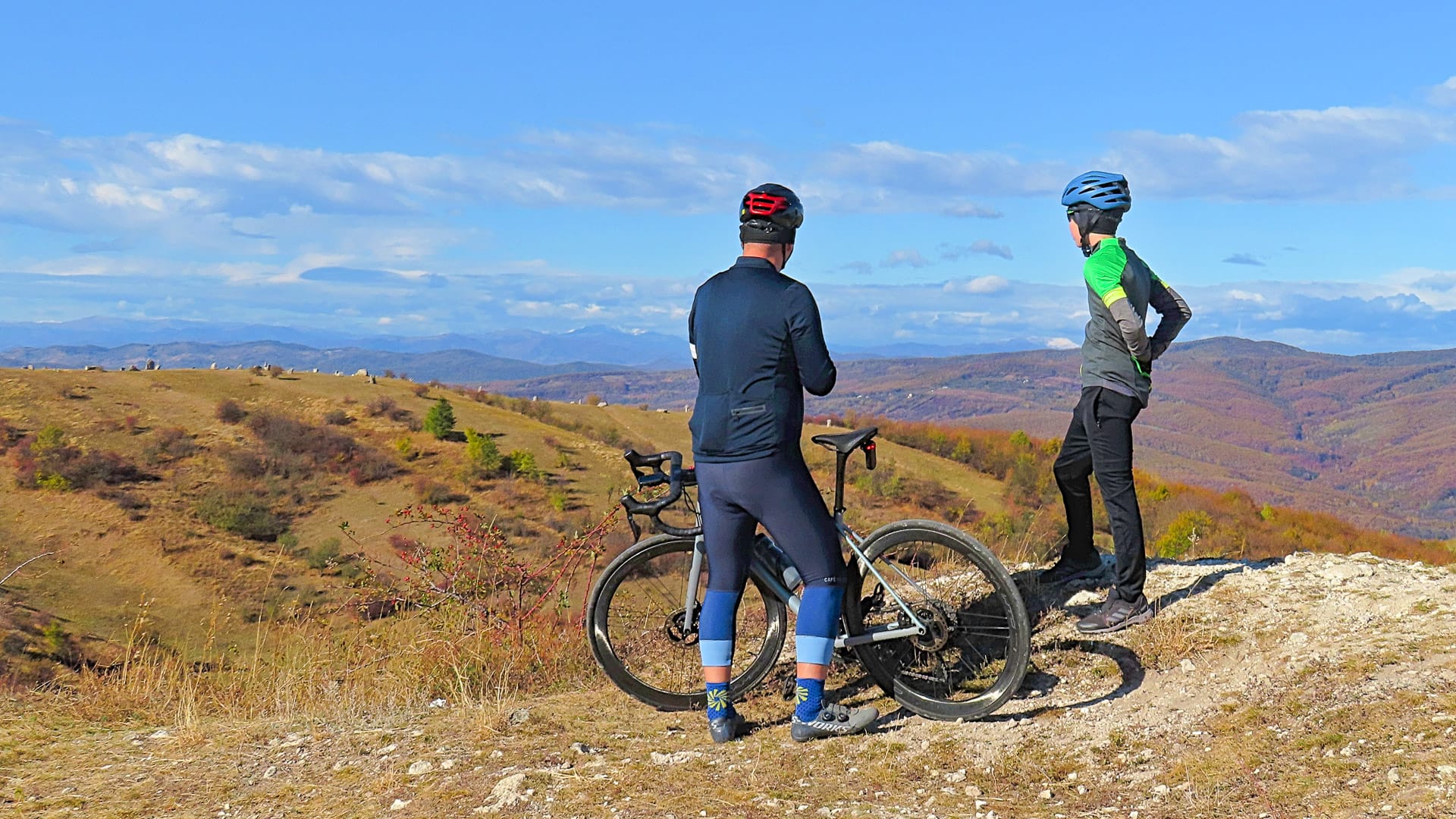 Gravel wine tour near Bucharest with cyclists dressed in long sleeves overlooking vineyard scenery