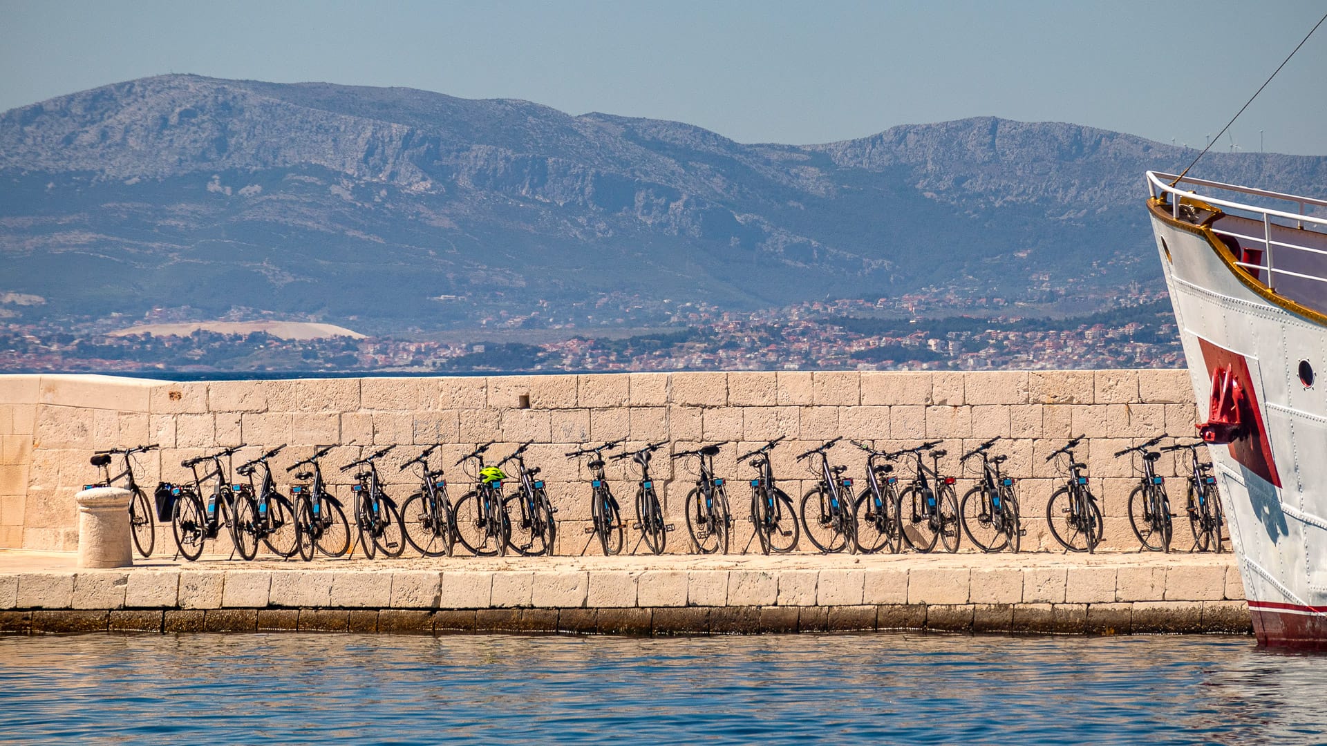 Port and pier of village Postira on island Brac in Croatia with tourist boat and cycles