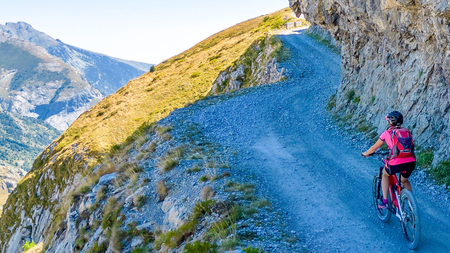 Cyclists passing beneath Pertegà peak rock face on Upper Salt Road