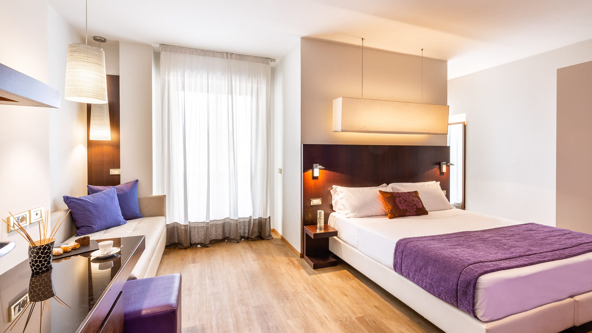 Spacious suite with violet accents and natural light from a large wall window