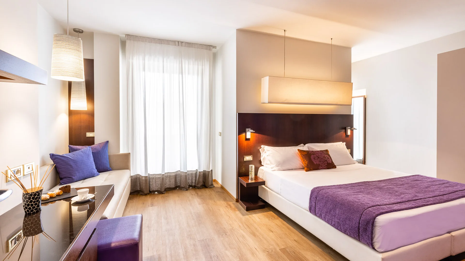 Spacious suite with violet accents and natural light from a large wall window