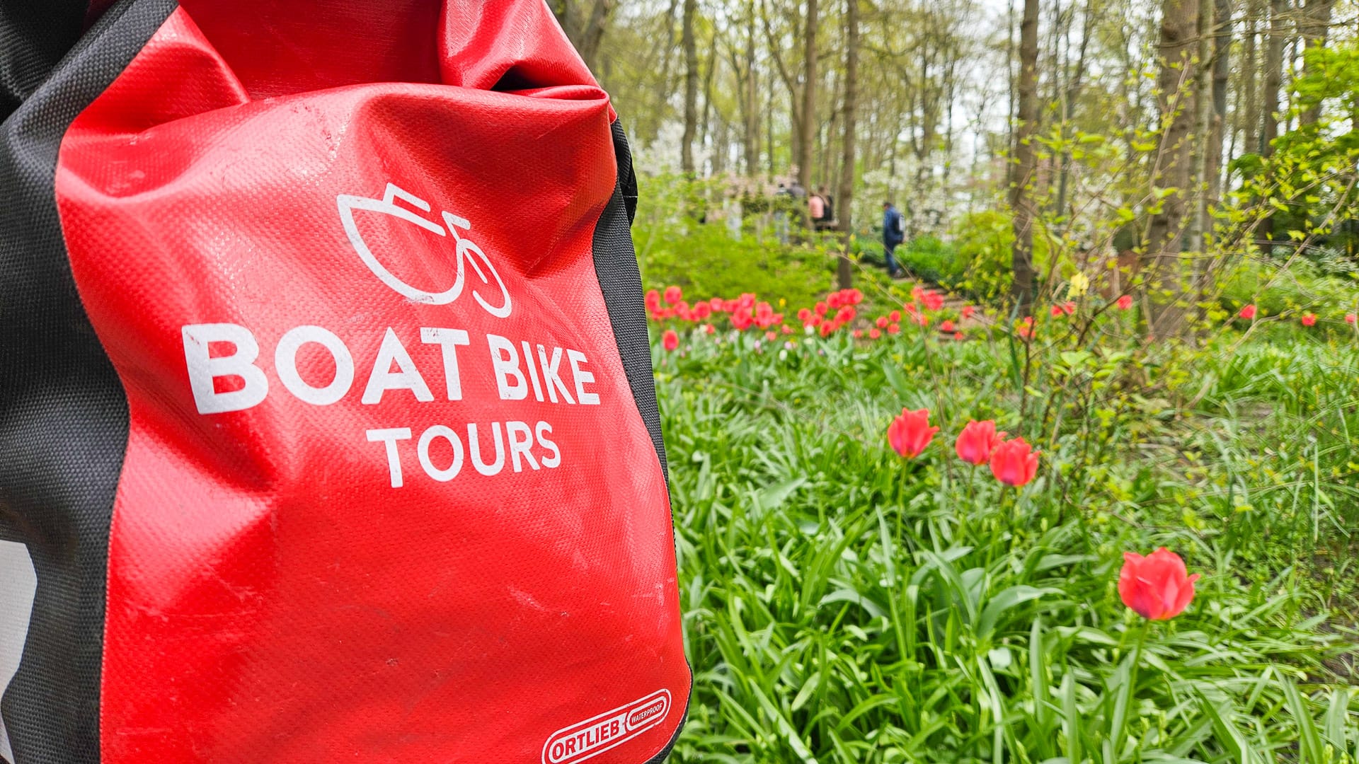 Cycle tourer bag with Boat Bike Tours print set against colourful tulip fields in the Netherlands