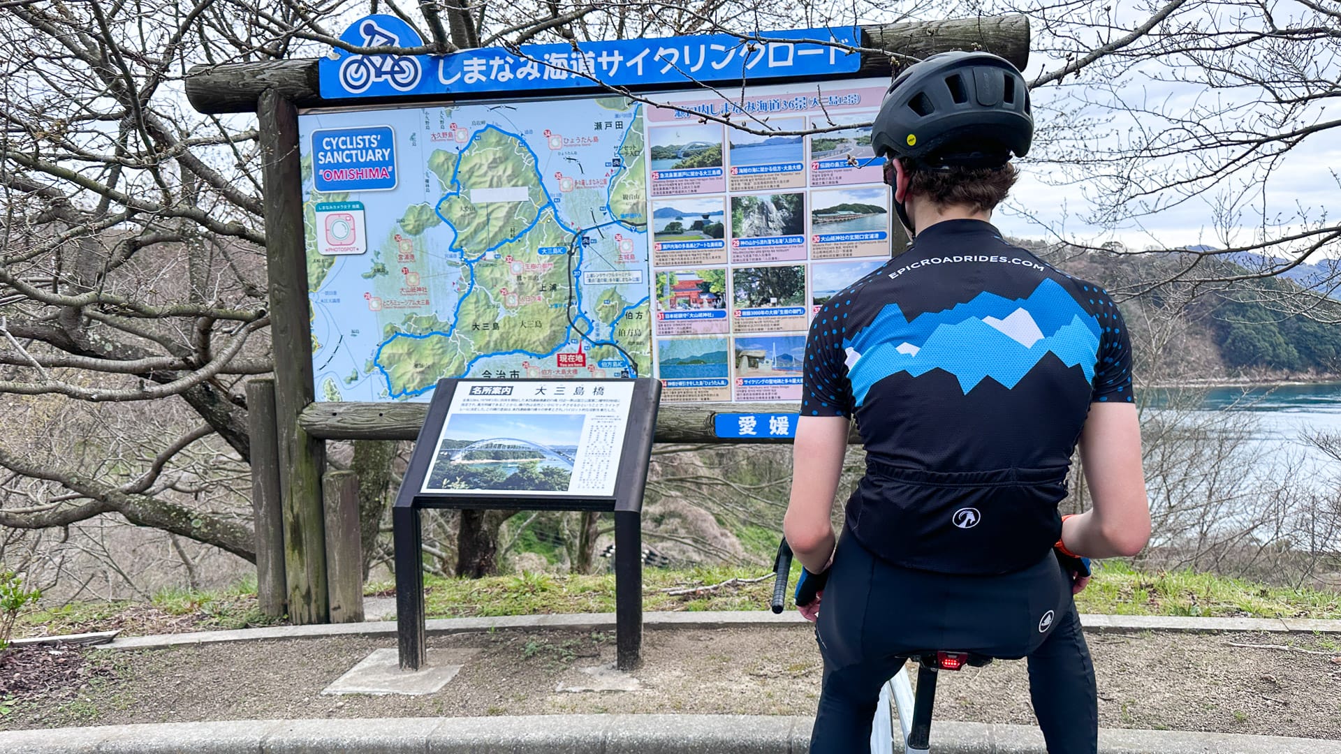 Cyclist checking route map sign near Hakata Bridge on Shimanami Kaido, Japan