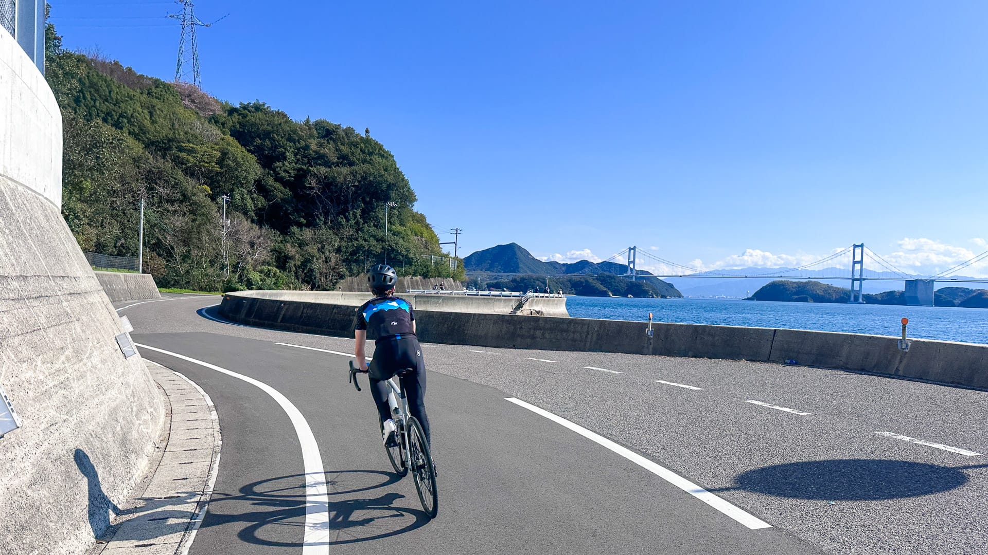 Cyclists riding on Oshima Island in Japan on day two with coastal sea views