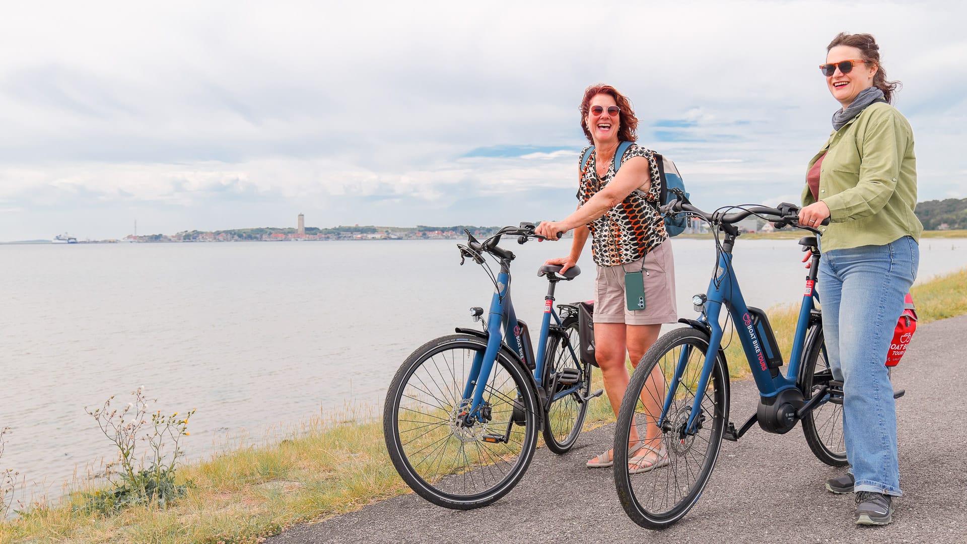 Cyclist laughing on Terschelling with Brandaris lighthouse on horizon, Wadden Sea Netherlands