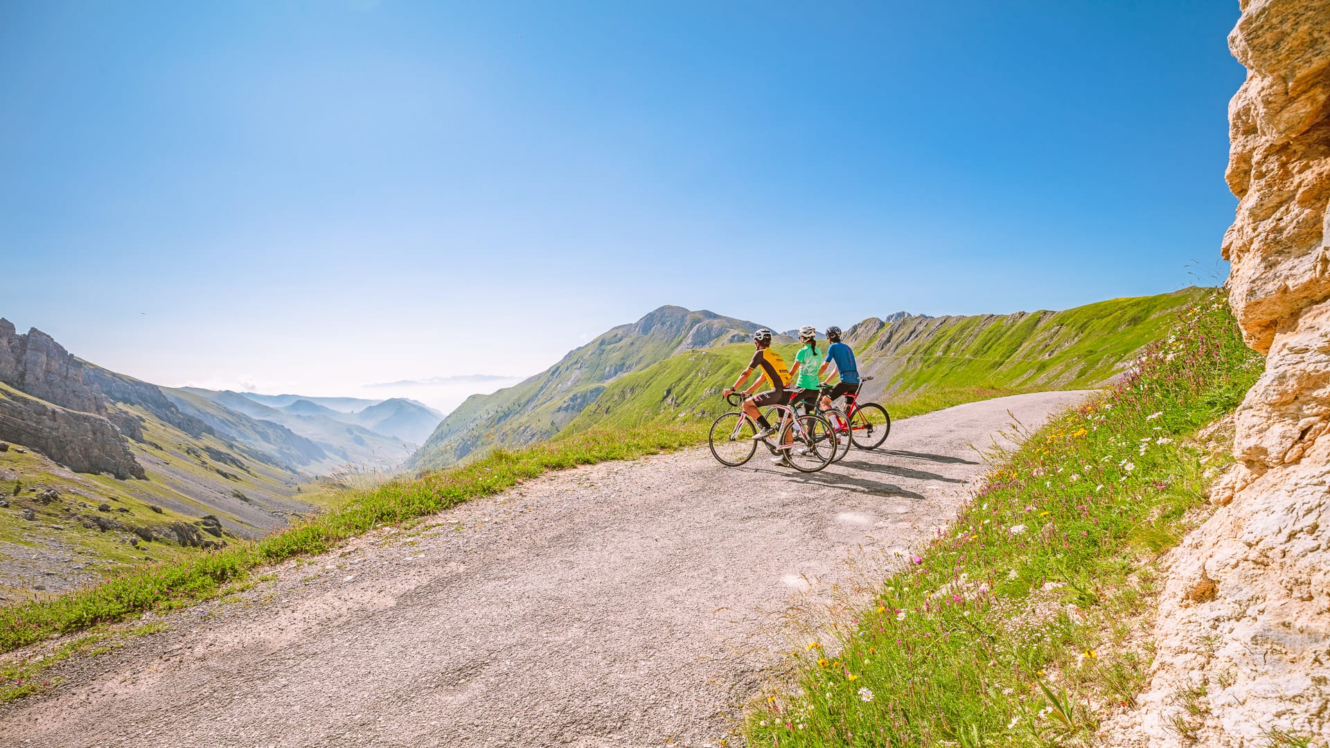 Cyclists riding through Grana Valley with panoramic mountain views