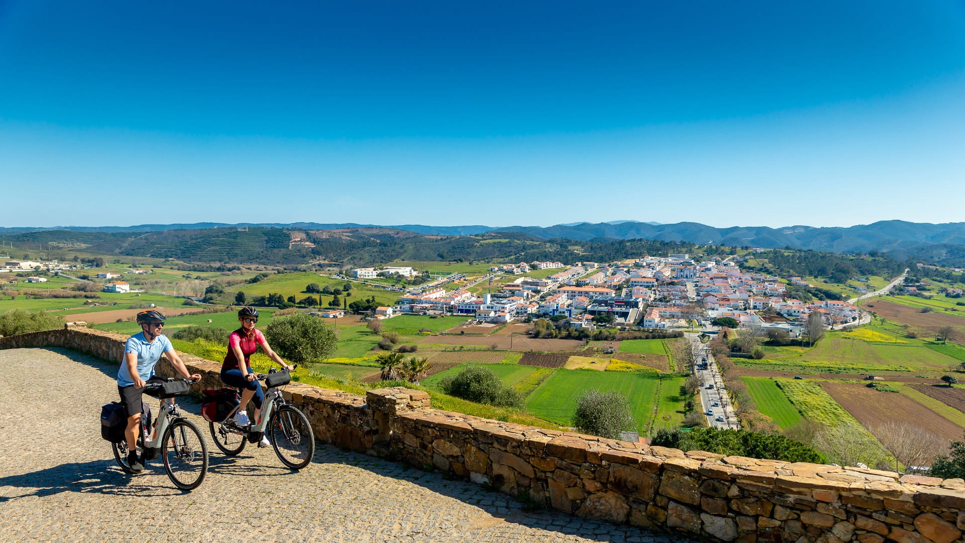 Cyclist climbing towards the medieval castle in Aljezur on the EuroVelo 1 route
