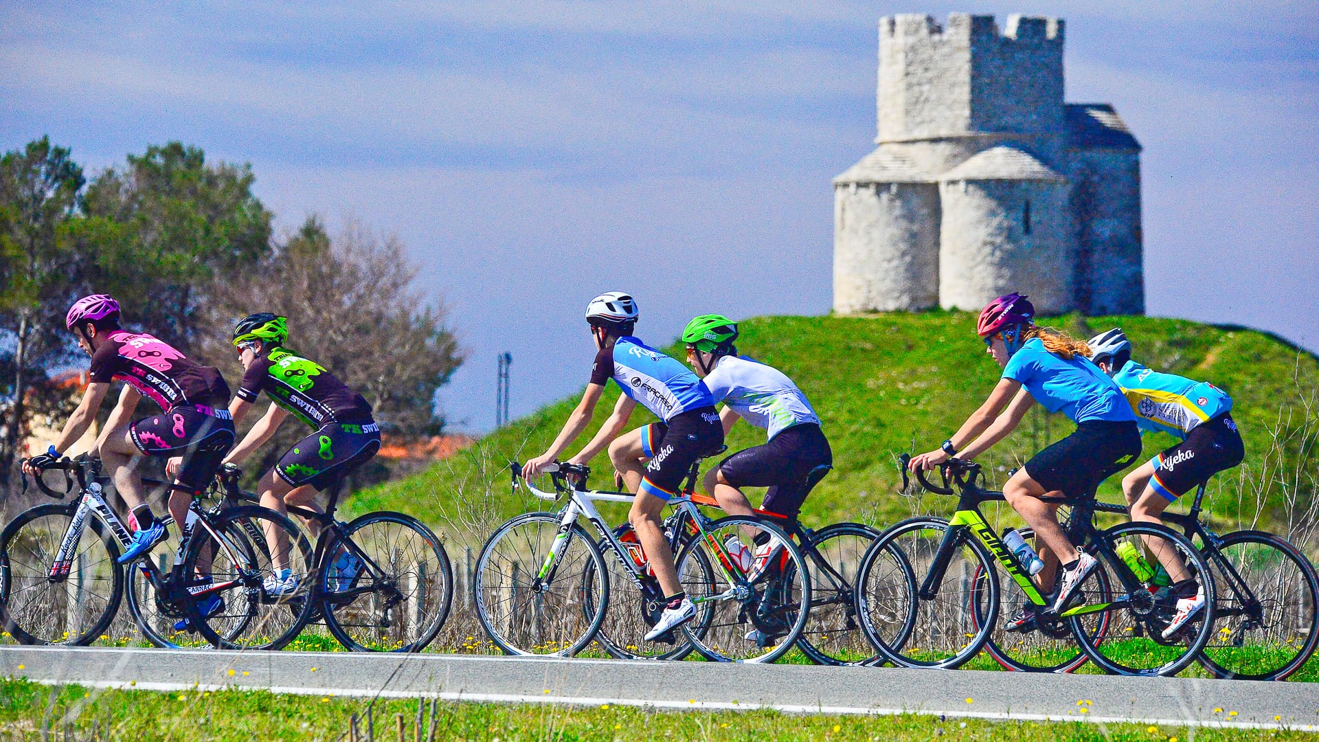 Riders tackling the Nin cycling route with historic Church of St. Nicholas in the background