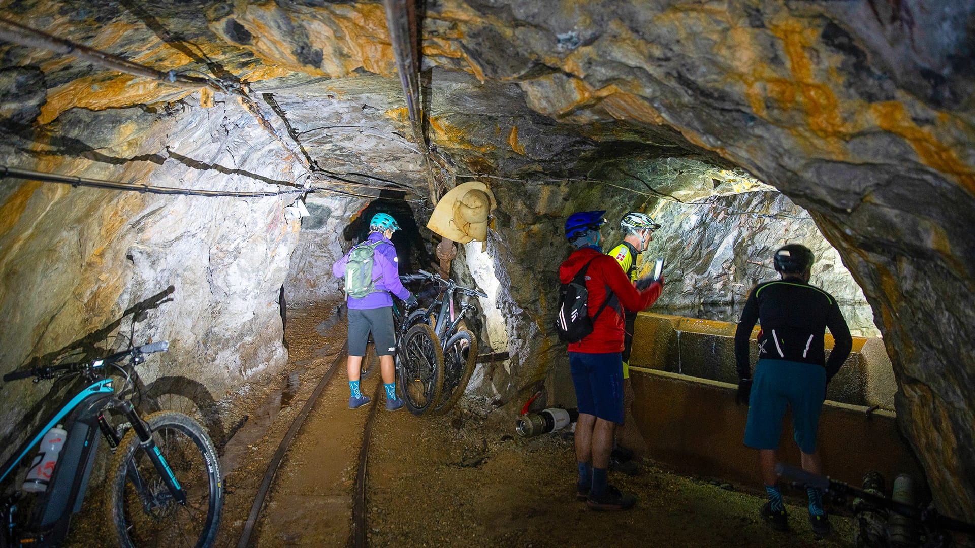 Cyclists riding through a cave-like tunnel in Val Germanasca, Piemonte