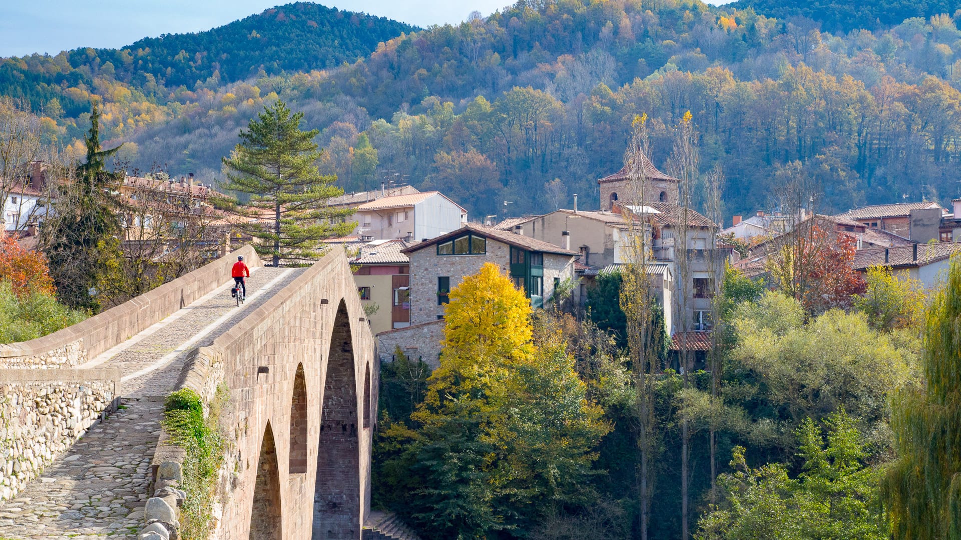 Cyclists passing by historic architecture in Sant Joan de les Abadesses, Girona