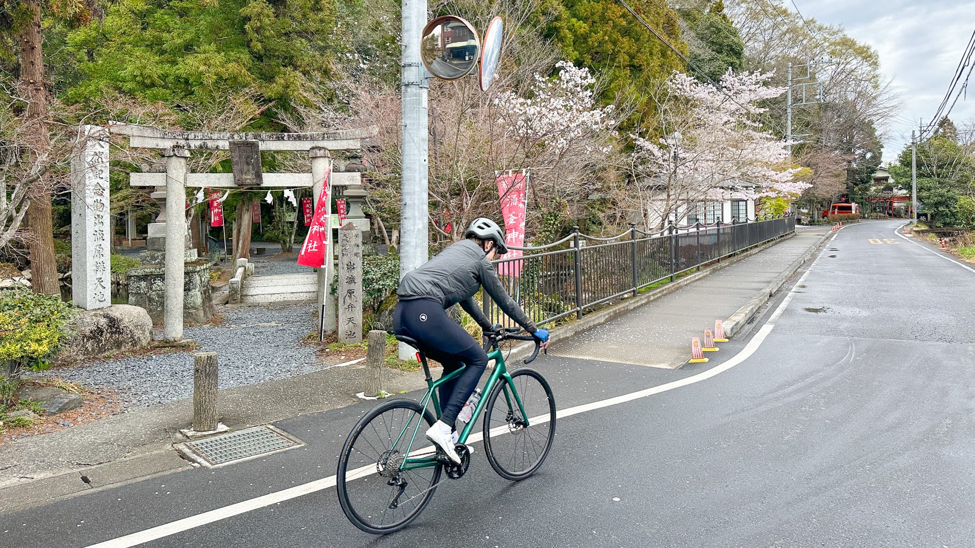 Cyclist riding past a roadside shrine on the Nikko to Ashikaga route in Japan