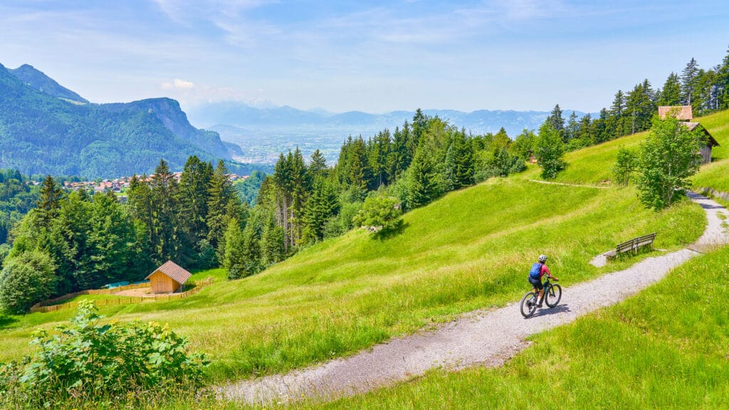 Woman riding a bike in the Bregenzerwald mountains above Dornbirn and the Rhein Valley, Vorarlberg, Austria