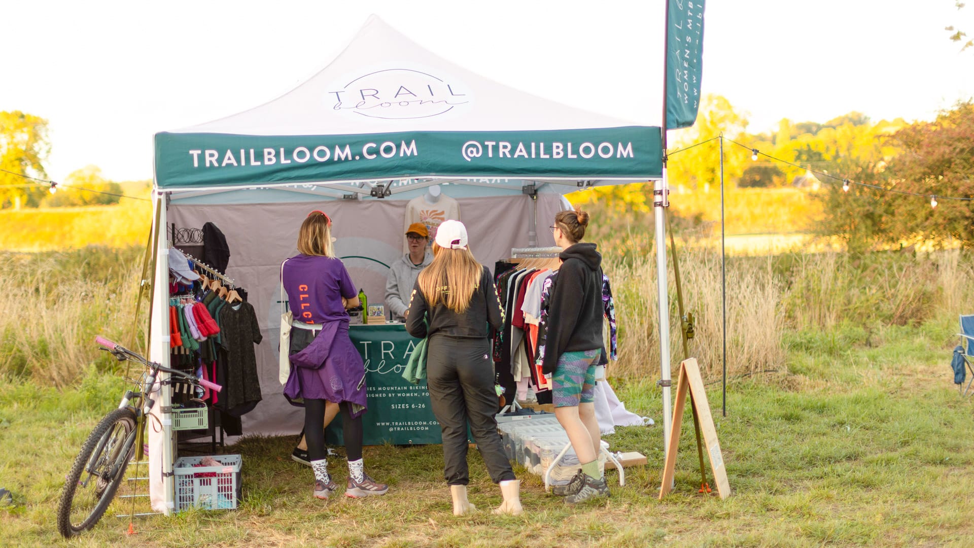 Girl cyclists gathered beside a Trailbloom tent during a cycling event in Dorset