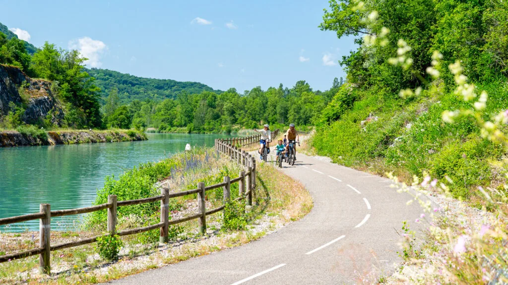 Cyclists riding Le Haut-Rhône around Massignieu-de-Rives, with quiet riverside roads and green countryside