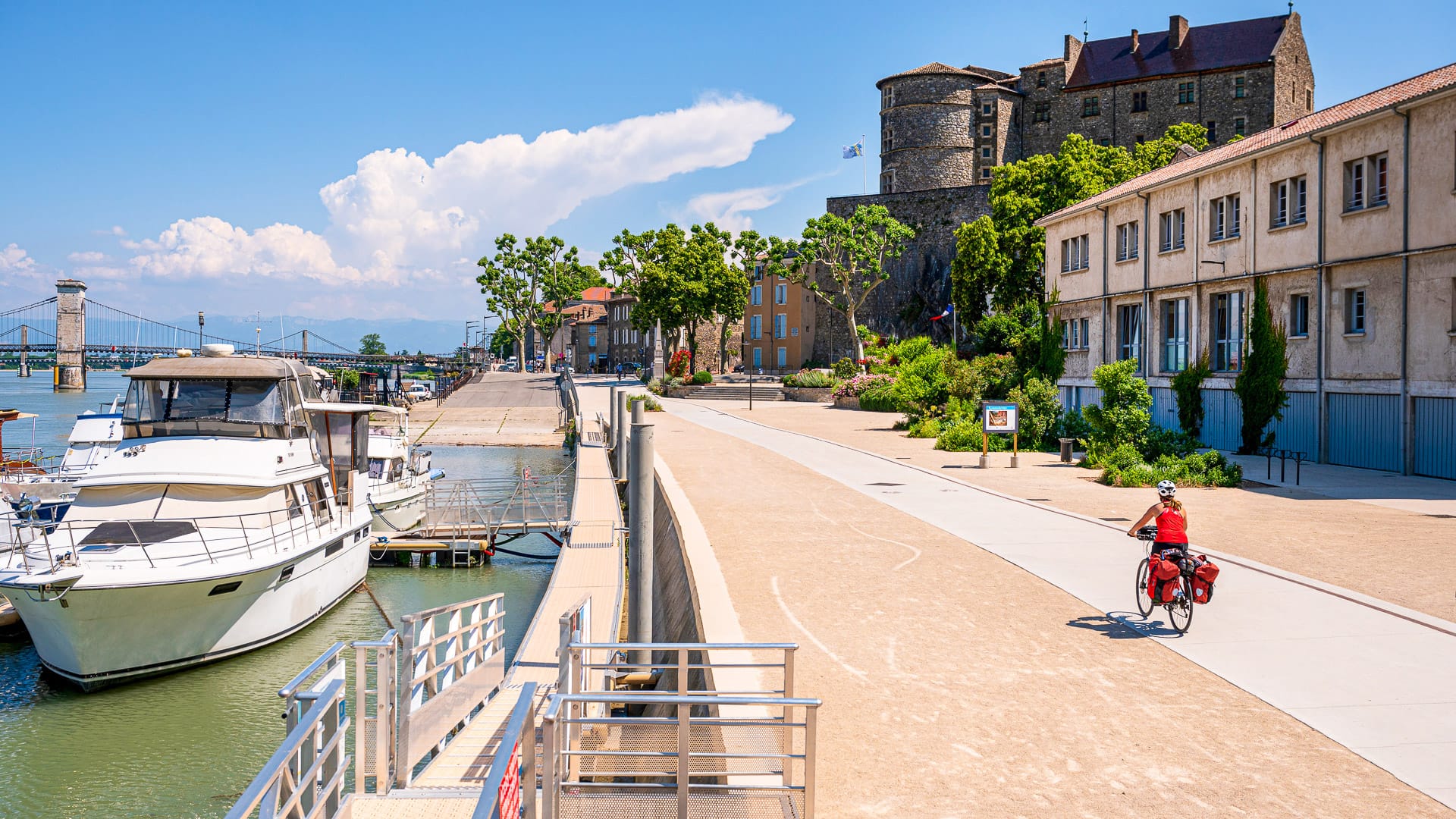 Cyclist on the ViaRhôna quays in Tournon-sur-Rhône, beside the Rhône and riverside buildings