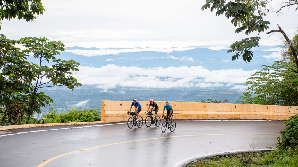 Cyclist climbing a paved road in the Alto de Letras region with sea of clouds in the background