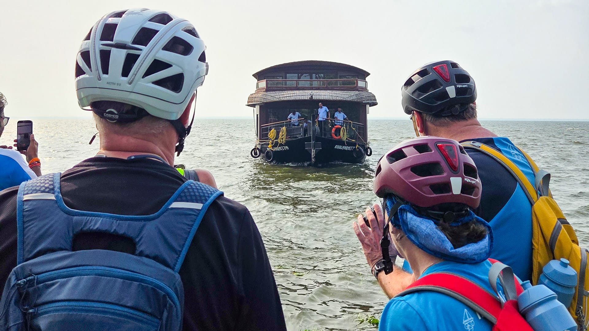 Cyclists waiting to board a houseboat in the Kerala Backwaters, India