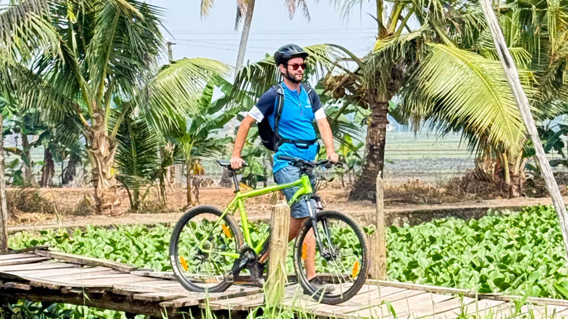 Cyclist walking with his bike through the Kerala Backwaters, India