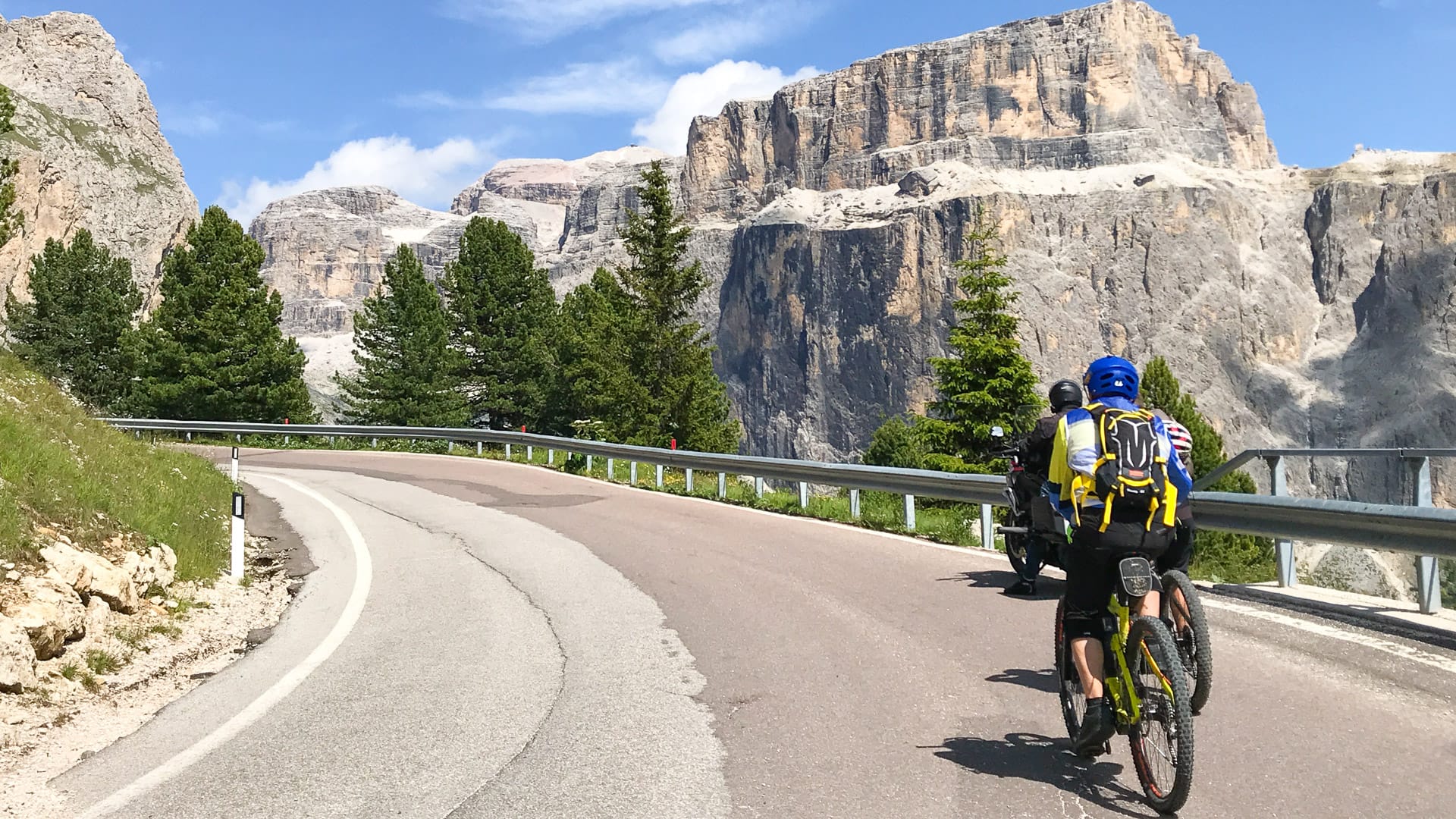 Cyclists riding towards Santa Cristina in the Italian Dolomites, Northern Italy.