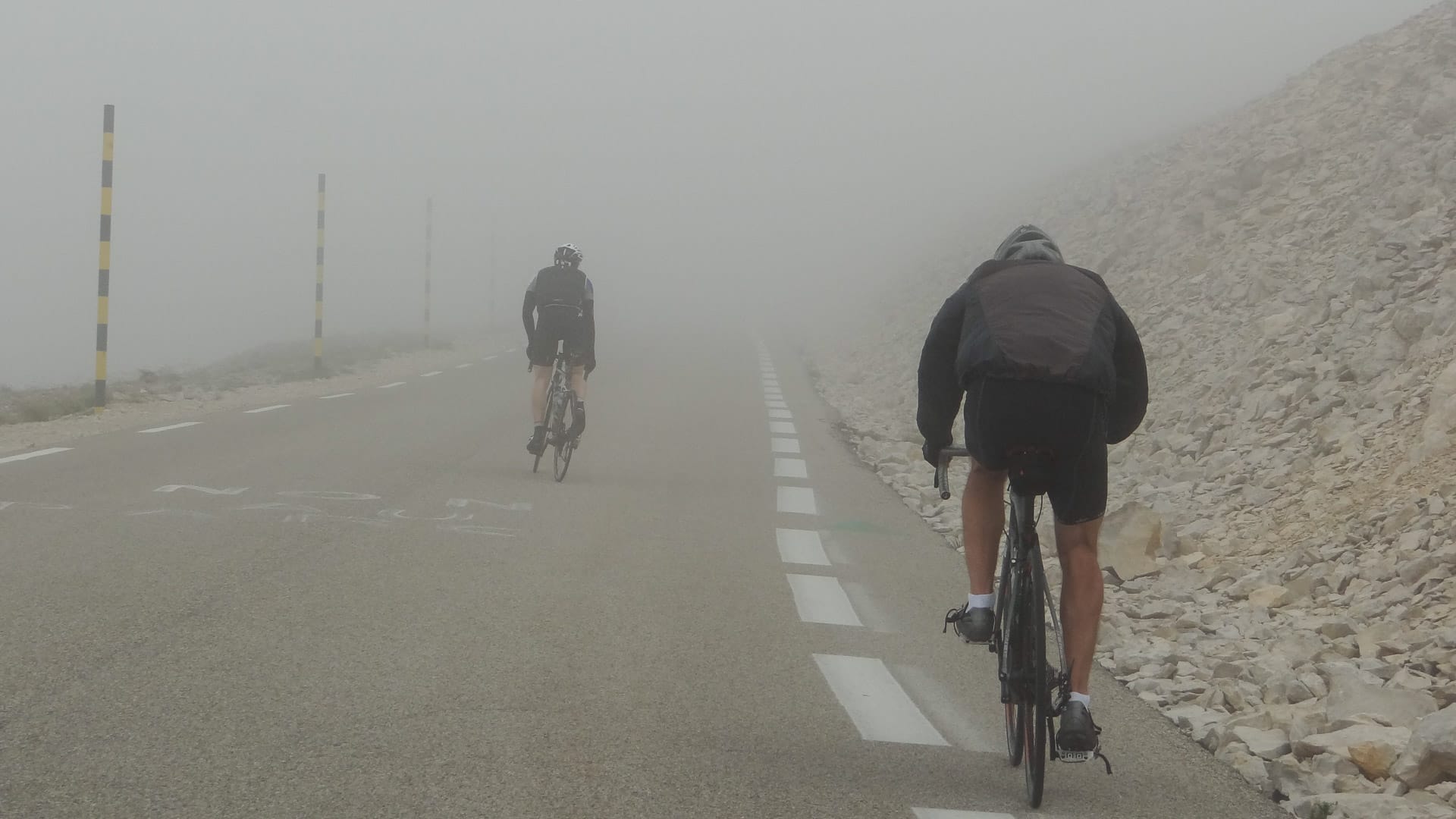 Cyclists riding through thick fog near the summit of Mont Ventoux on the Sault route