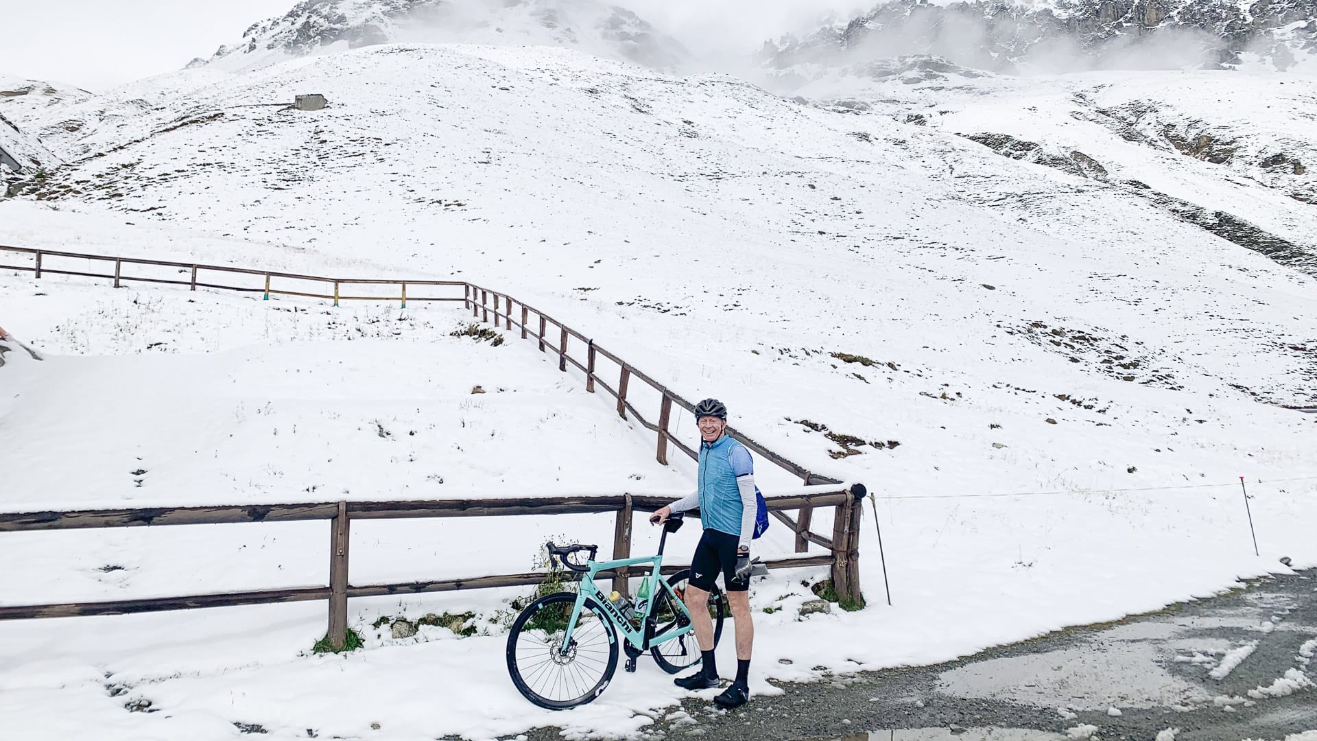 Cyclist and his bike in the snow on the way up Stelvio Pass in the Italian Alps