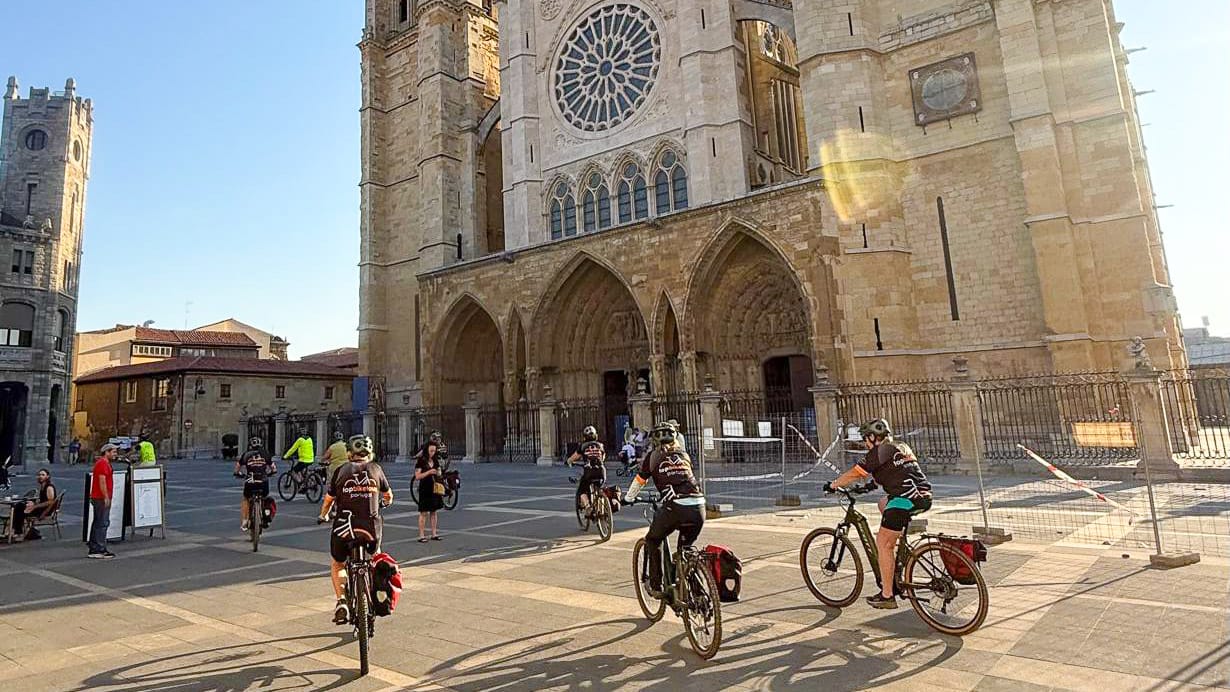 Cyclists riding past León Cathedral on the Camino Francés